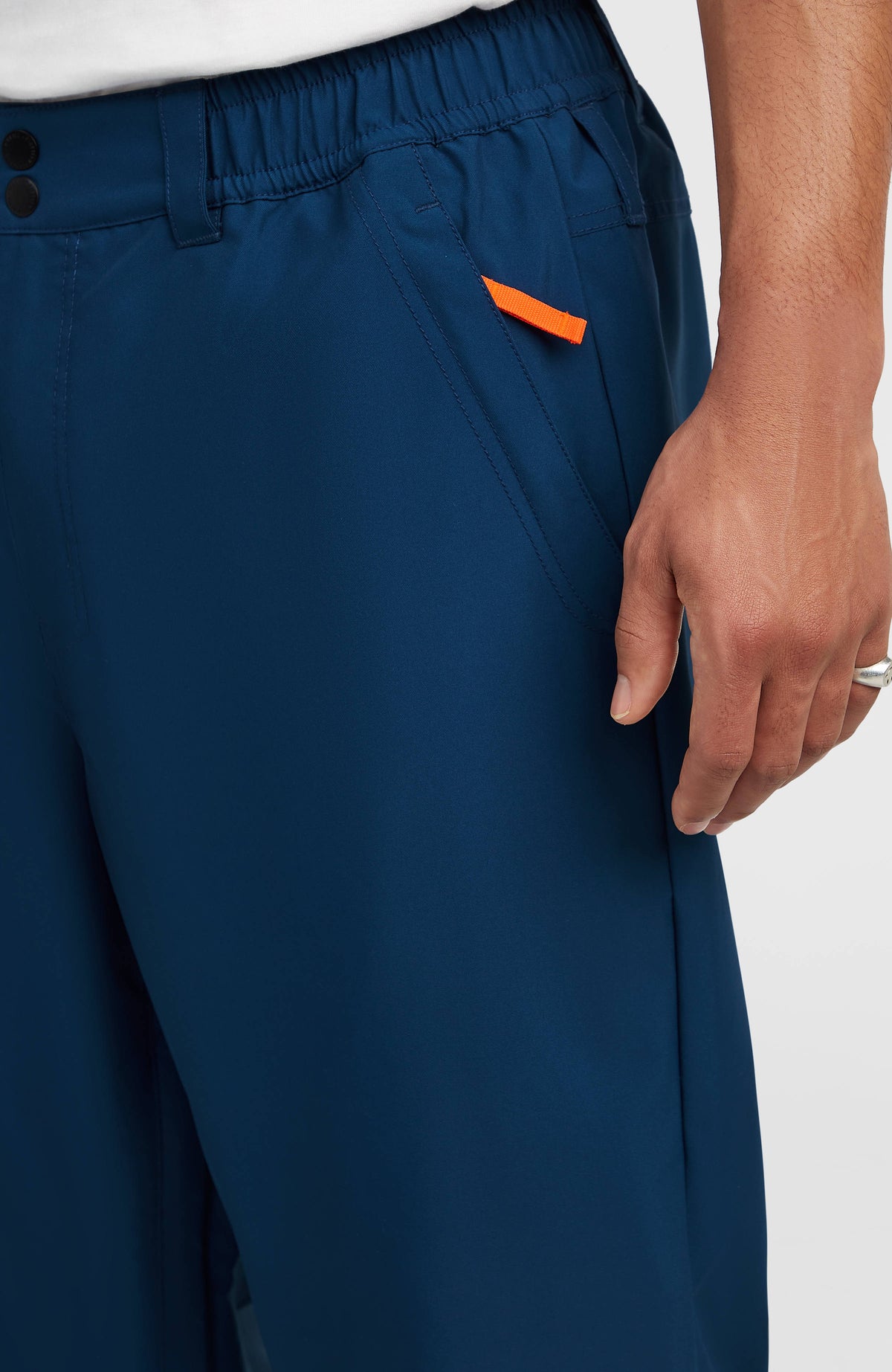 Nahaufnahme der Eingrifftasche mit oranger Lasche der blauen FWC Oversized Ski- und Snowboardhose
