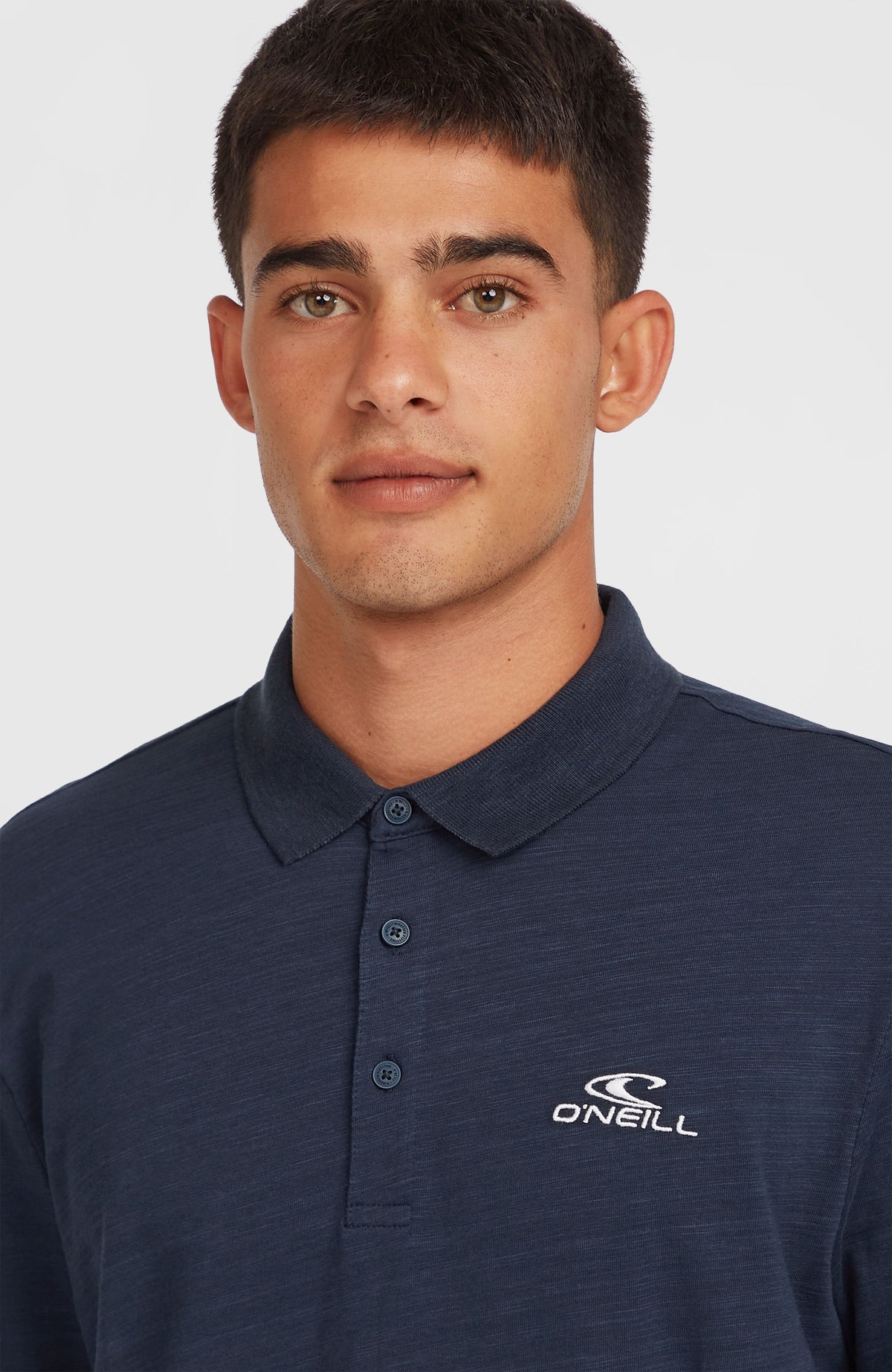 Nahaufnahme von Kragen und Knopfleiste des blauen Slub Small Logo Poloshirt am Model