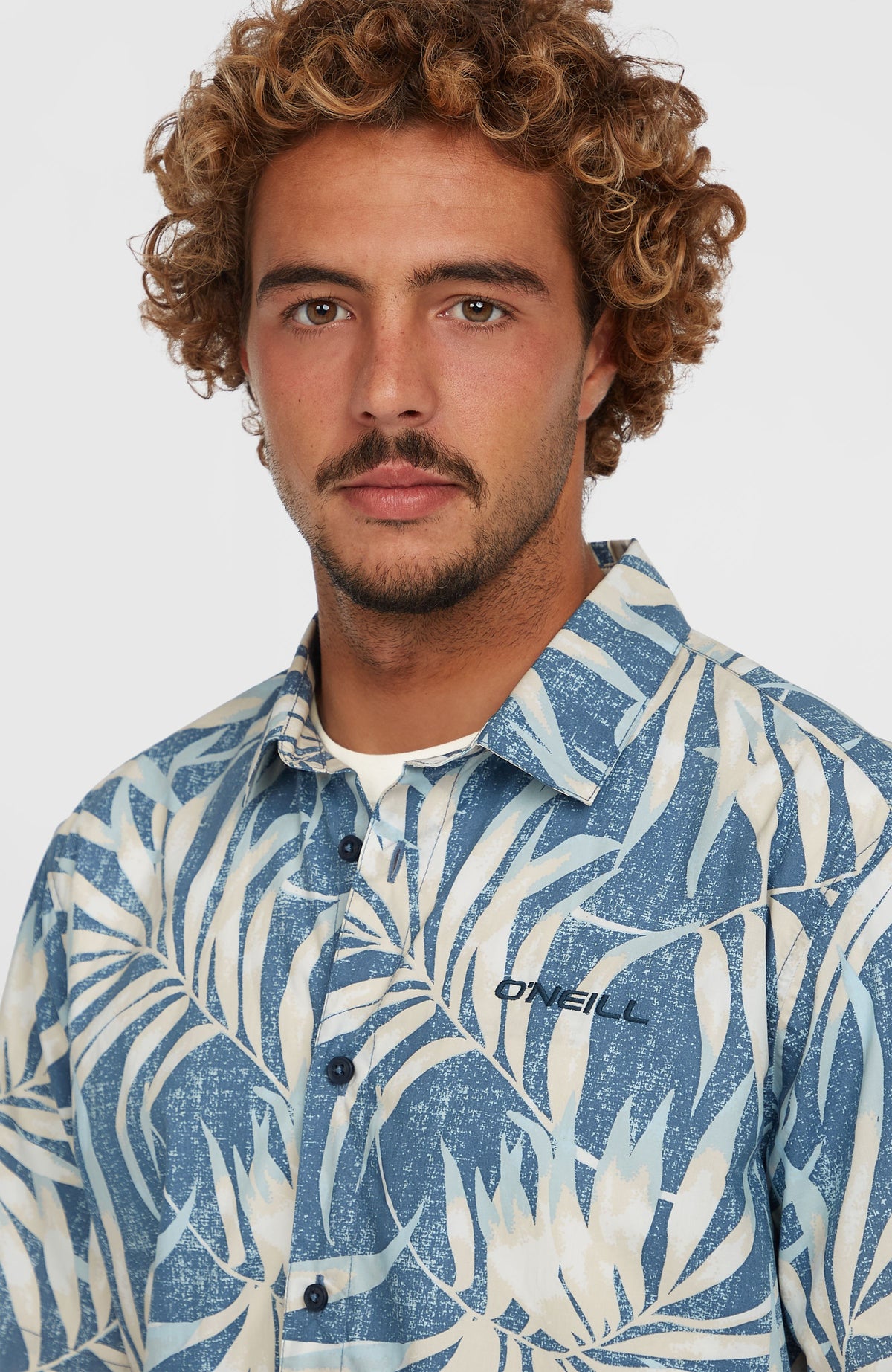 Nahaufnahme von Kragen, Knopfleiste und Logo-Stickerei des blauen Print-Shirts am Model