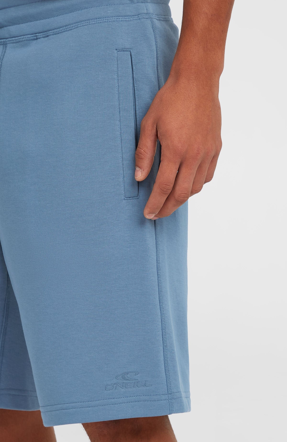 Nahaufnahme der Seitentasche und des Saums mit dezentem Logo der blauen Small Logo Sweatshorts