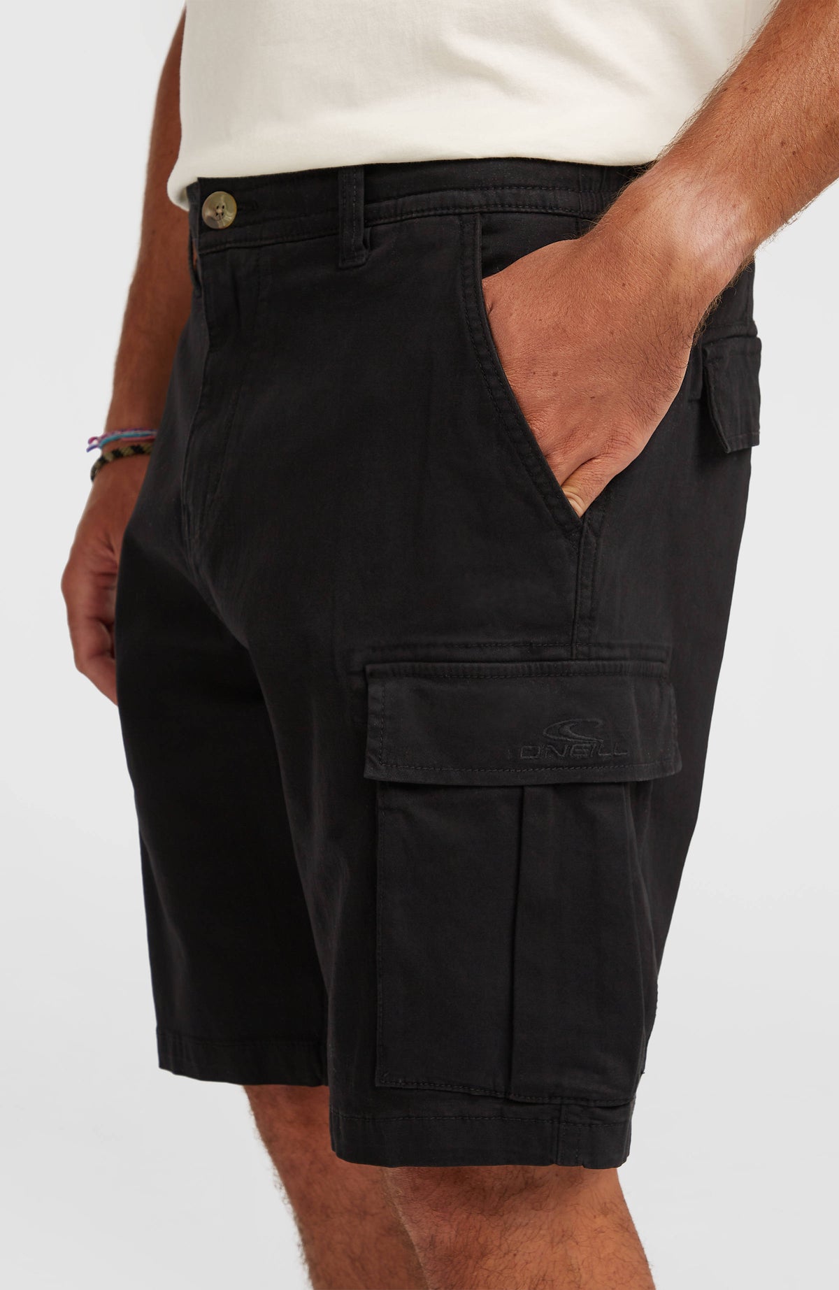 Nahaufnahme der schwarzen Essentials Cargo-Shorts, aufgesetzte Cargotasche mit Klappe und Logo-Stickerei