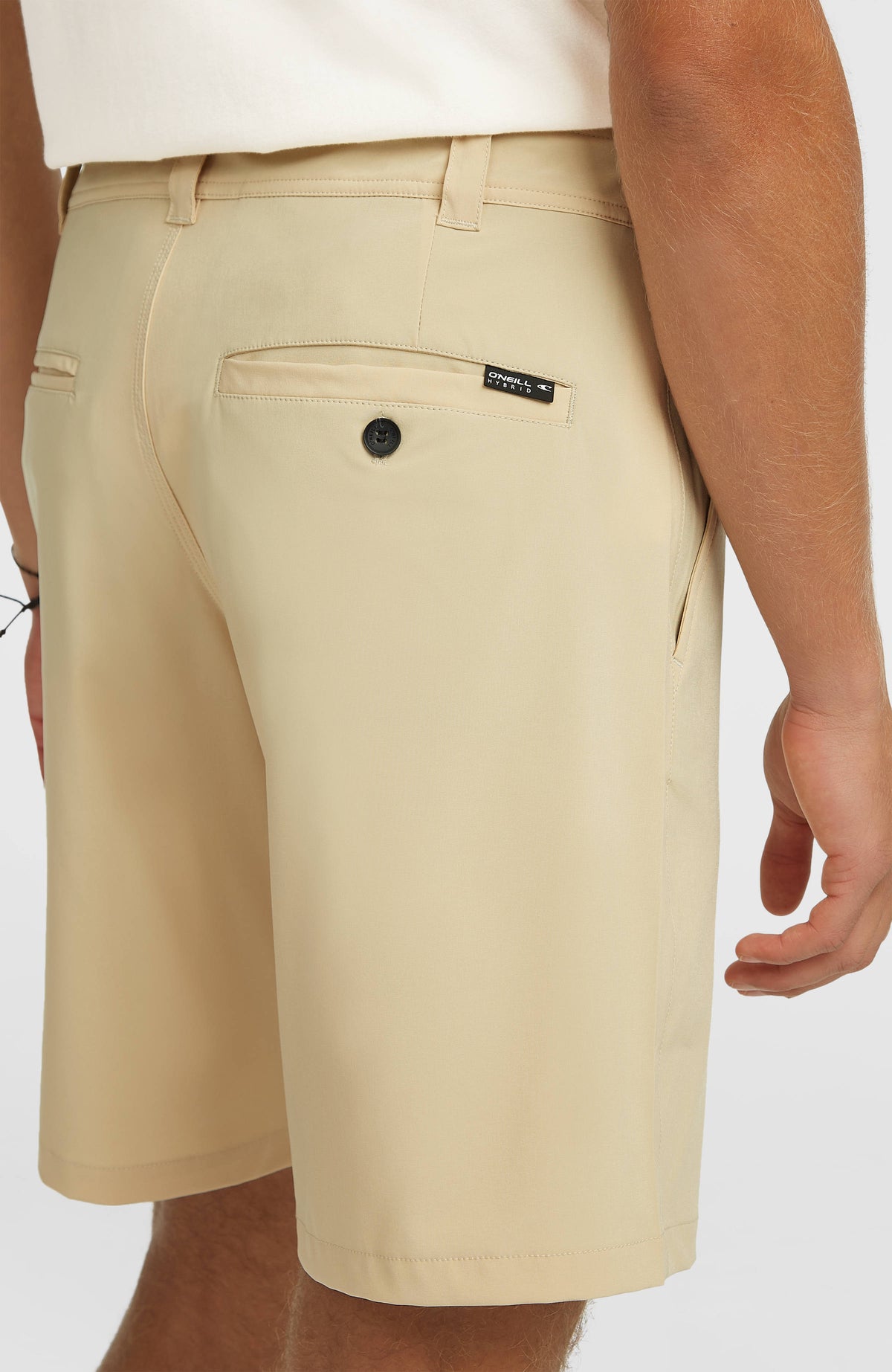 Nahaufnahme der hinteren Tasche mit Knopf und Logo-Label der beigen Hybrid 19" Shorts
