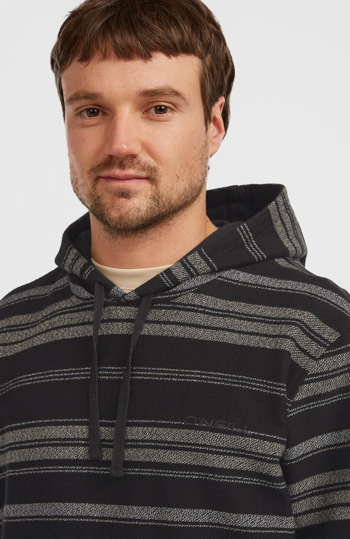 Nahaufnahme des schwarzen BAVARO HOODIE am Model, dezenter Logo-Schriftzug auf der Vorderseite und Kordelzug