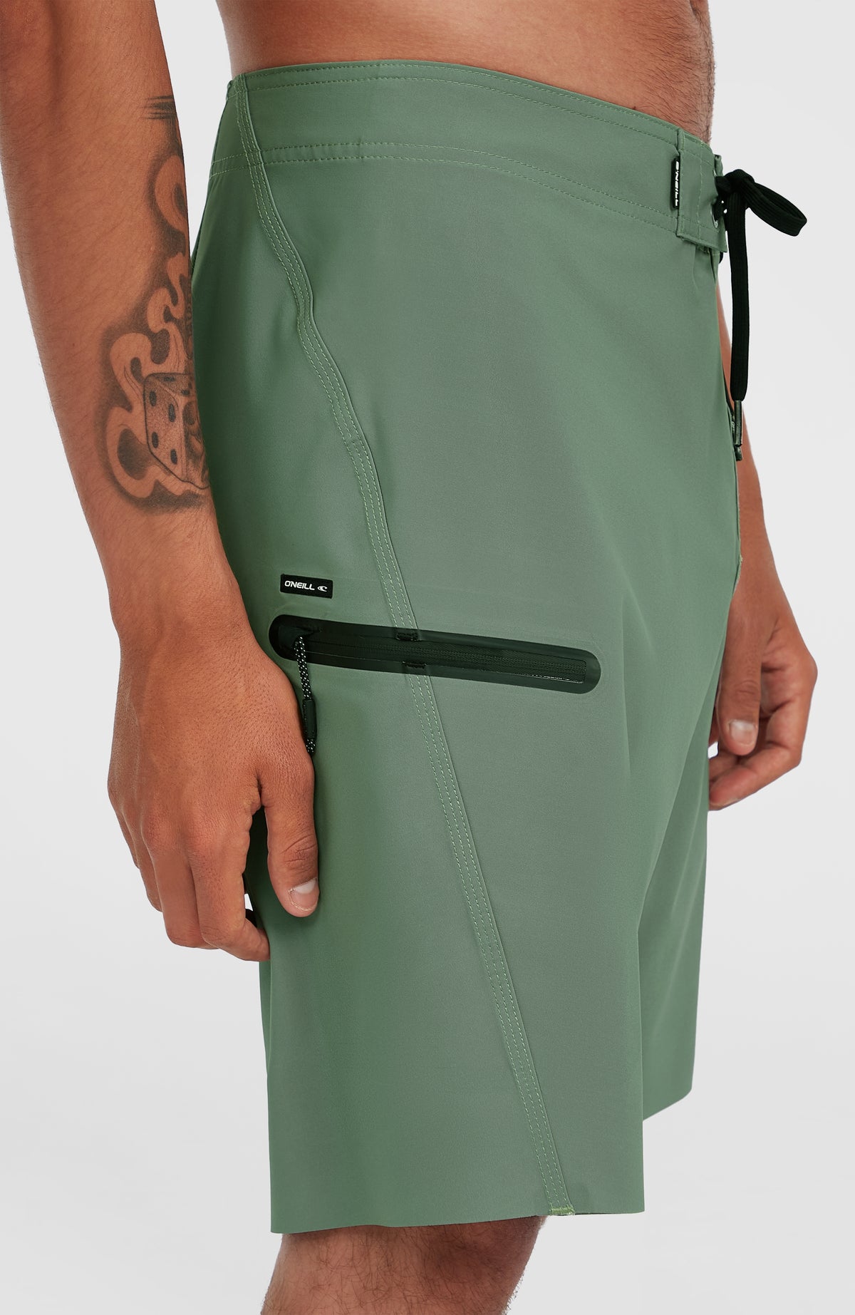 Nahaufnahme der seitlichen Reißverschlusstasche der grünen Hyperfreak Tech Solid 19'' Boardshorts am Model