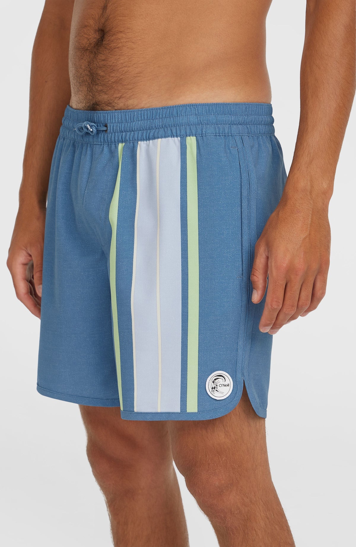 O'Riginals Scallop 16'' Badehose für Herren, blau mit Streifenmuster, Nahaufnahme am Model mit Logo-Patch am Saum