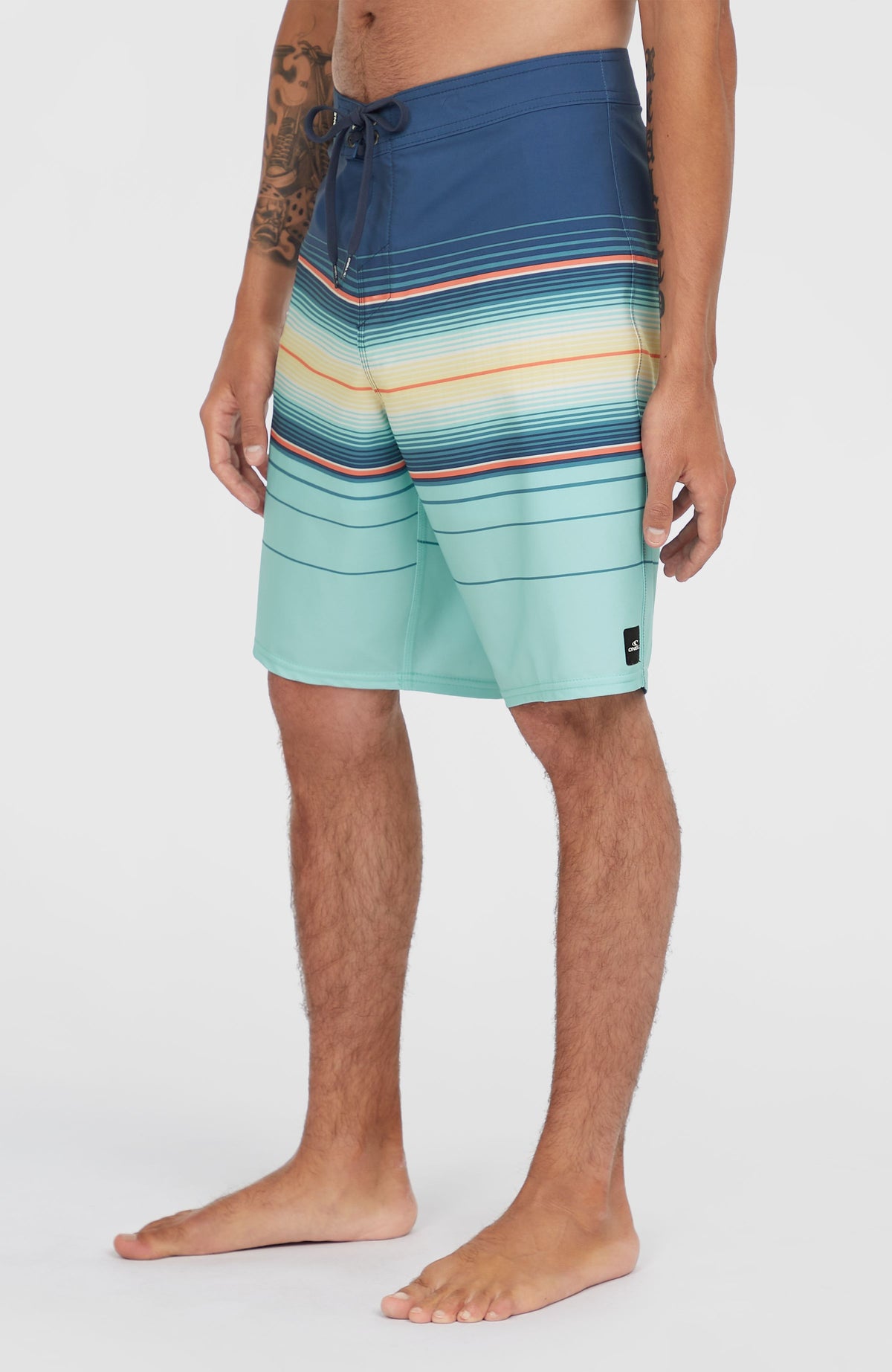 Hyperfreak Heat Stripe 21'' Boardshorts, blau mit Streifenmuster in Türkis und Gelb, Seitenansicht mit Logo-Patch am Saum