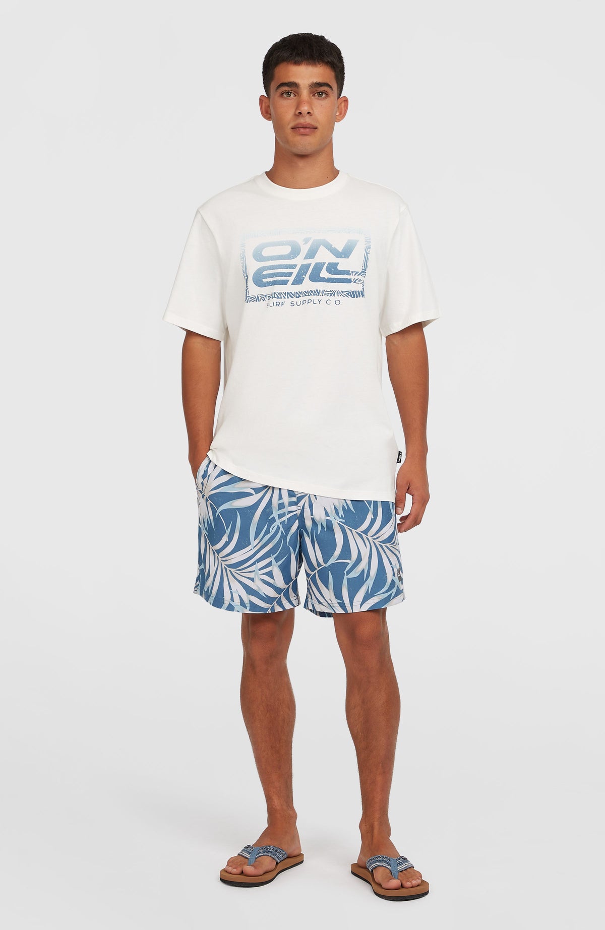 Cali Floral 16'' Badehose für Herren, blau mit Blättermuster in Weiß, getragen am Model in Ganzkörperansicht