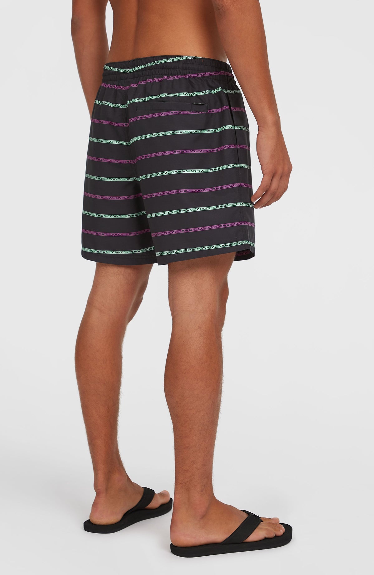 Cali First 15'' Badehose für Herren, schwarz mit Streifenmuster in Lila und Türkis, Rückansicht mit Gesäßtasche am Model