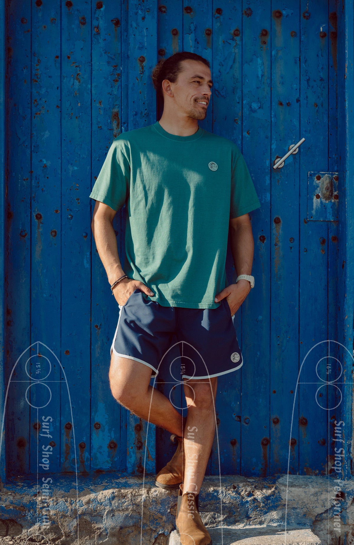 O'Riginals Scallop 16'' Badehose für Herren, blau, getragen am Model vor einer blauen Holztür
