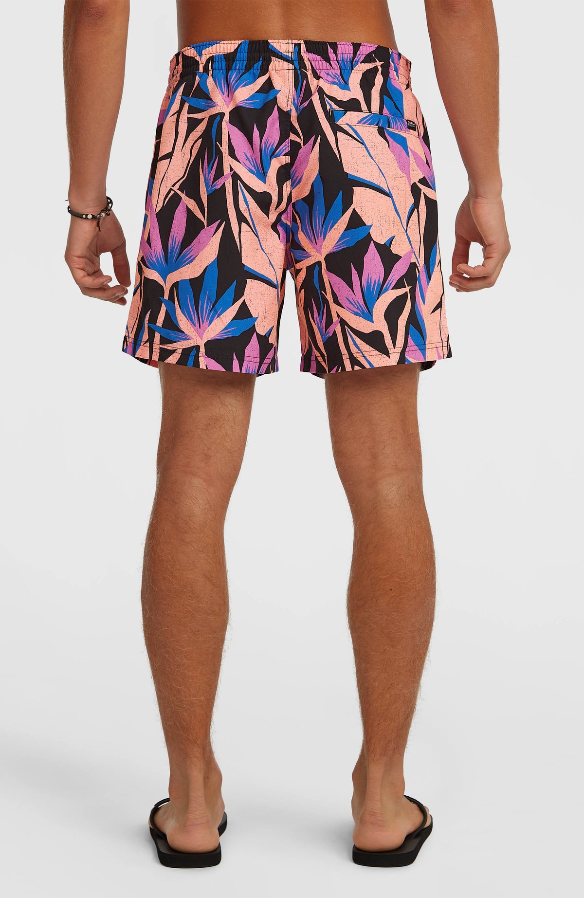 Print 16'' Badehose für Herren, schwarz mit Tropenmuster in Rosa und Blau, Rückansicht am Model mit Gesäßtasche