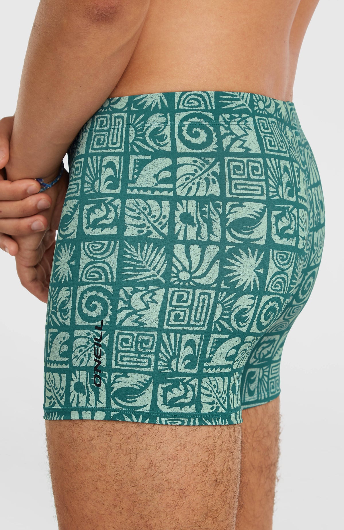 Nahaufnahme der blauen Essentials All-Over-Print Badehose mit Grafikmuster in Hellblau, Seitenansicht mit Logo-Print