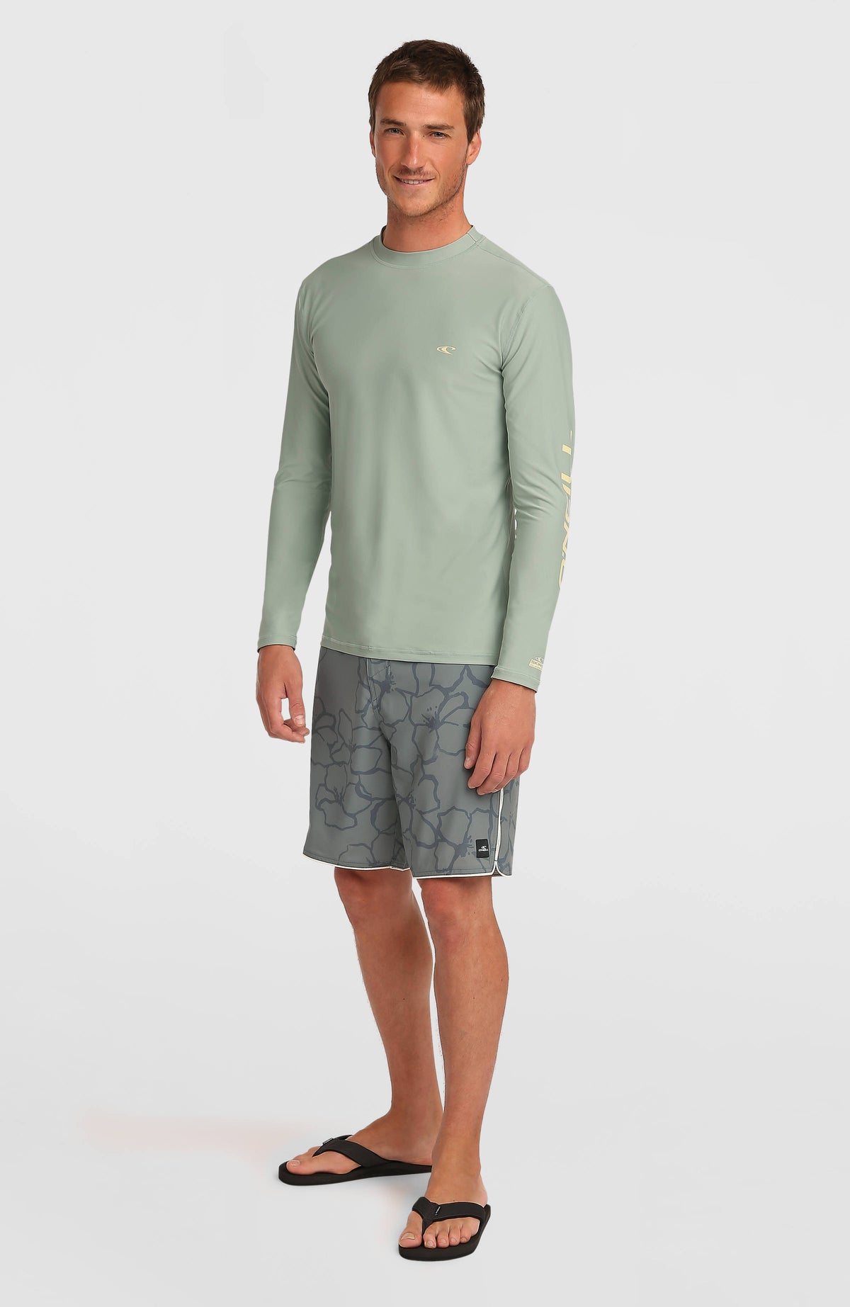 Grünes Longsleeve-UV-Shirt für Herren, Ganzkörperansicht am Model von schräg vorne mit Logo-Print am linken Ärmel