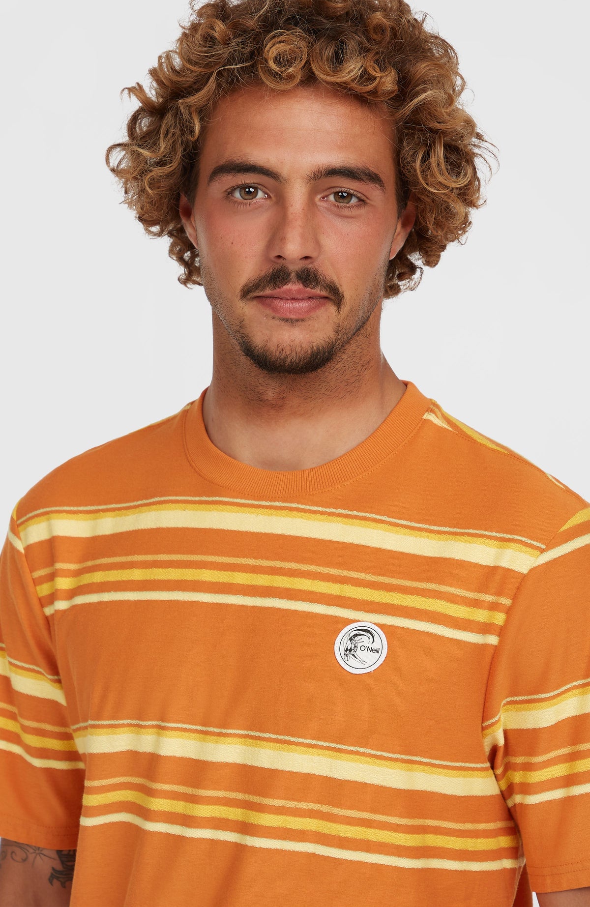 O'Riginals Stripe T-Shirt, orange mit Streifenmuster in Gelb und Weiß, Nahaufnahme von Rundhalsausschnitt und Logo-Badge