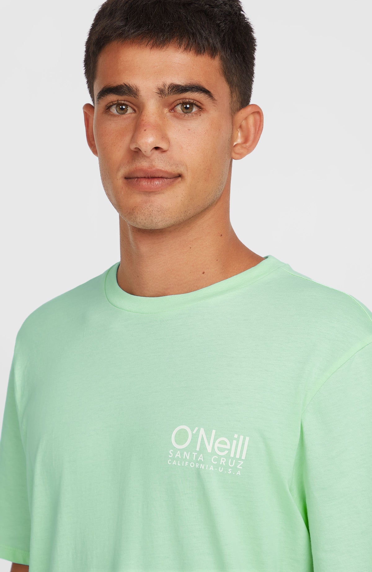 Original Cali Logo T-Shirt, grün mit Logo-Print in Weiß, Nahaufnahme des Brustbereichs am Model