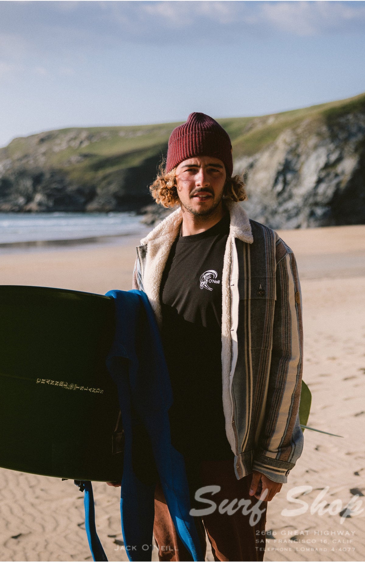 O'Riginals Hybrid T-Shirt, schwarz mit Logo-Print in Weiß, am Strand unter einer offenen Jacke getragen