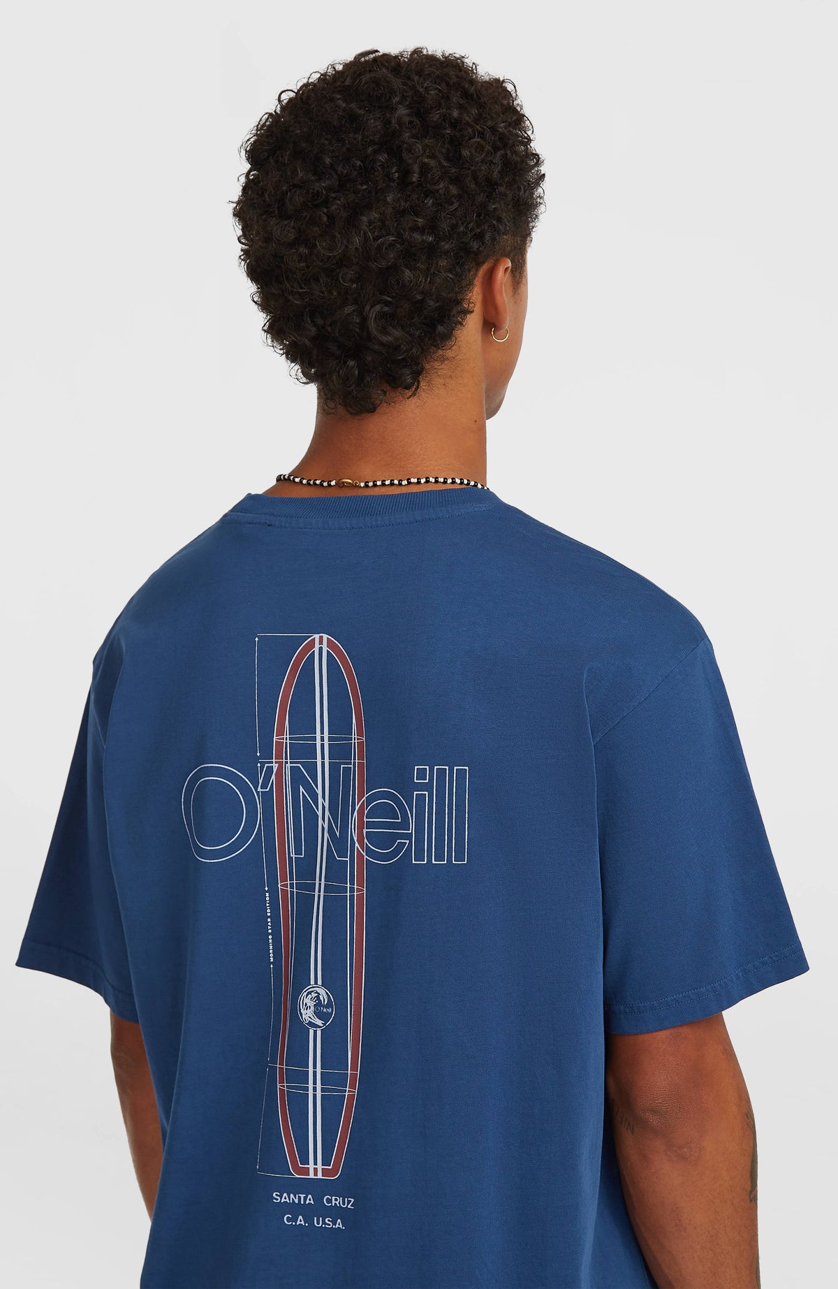 O'Riginals Vintage Graphic T-Shirt für Herren in Blau, halbe Rückansicht am Model mit großem Surfboard-Print