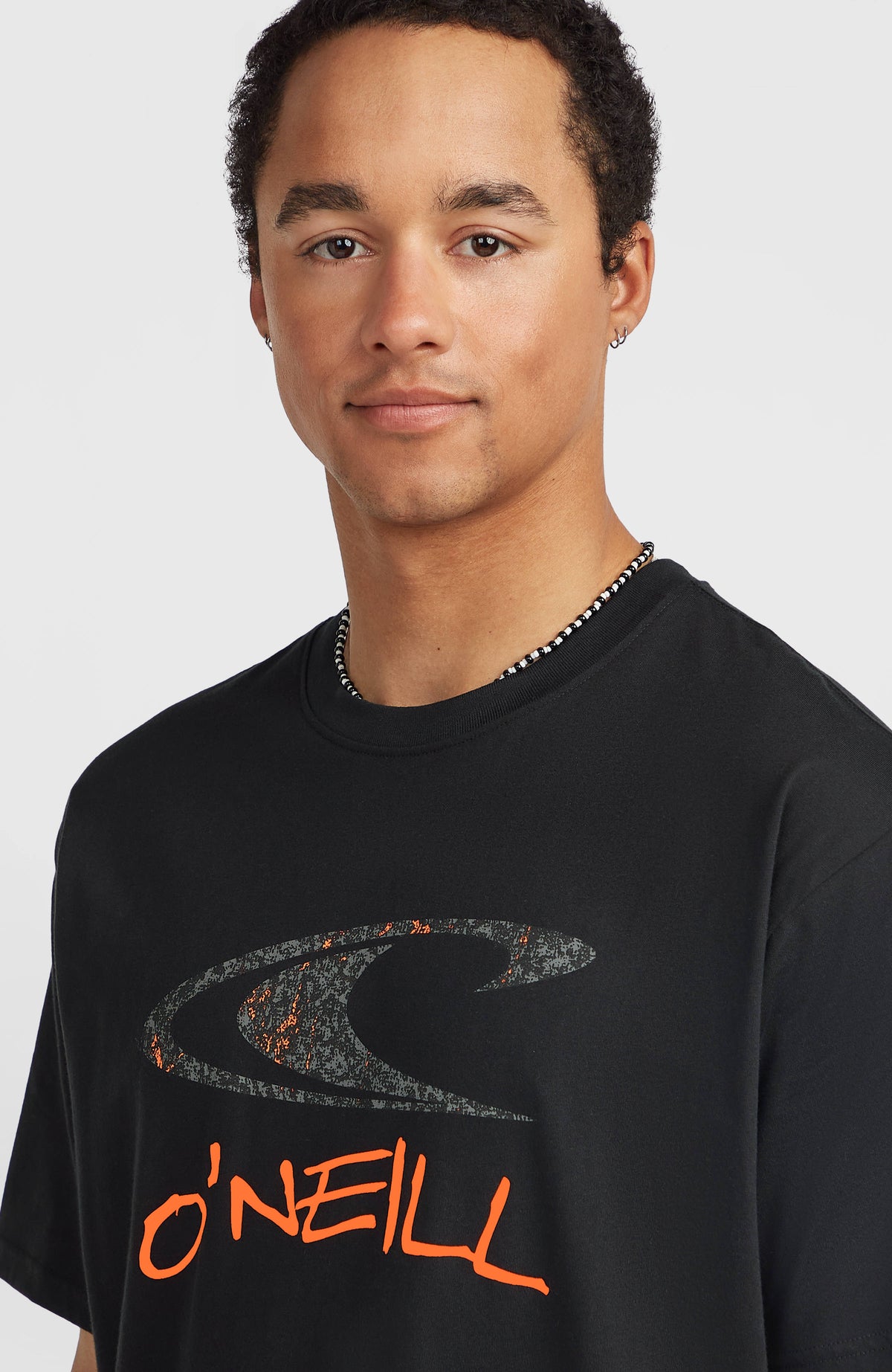 Must-Have Graphic T-Shirt, schwarz, Nahaufnahme am Model mit Logo-Print in Orange und Grau auf der Brust