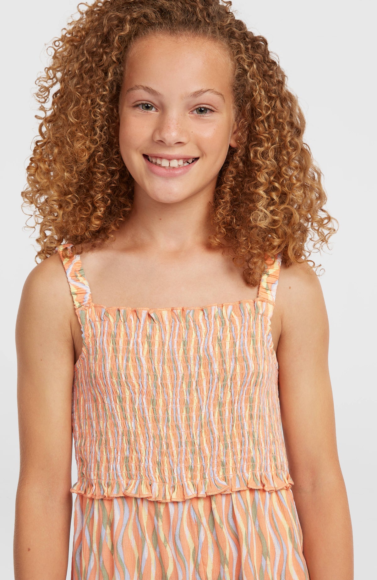 Woven Playsuit für Mädchen, orange mit Wellenmuster, Nahaufnahme des gesmokten Oberteils am Model