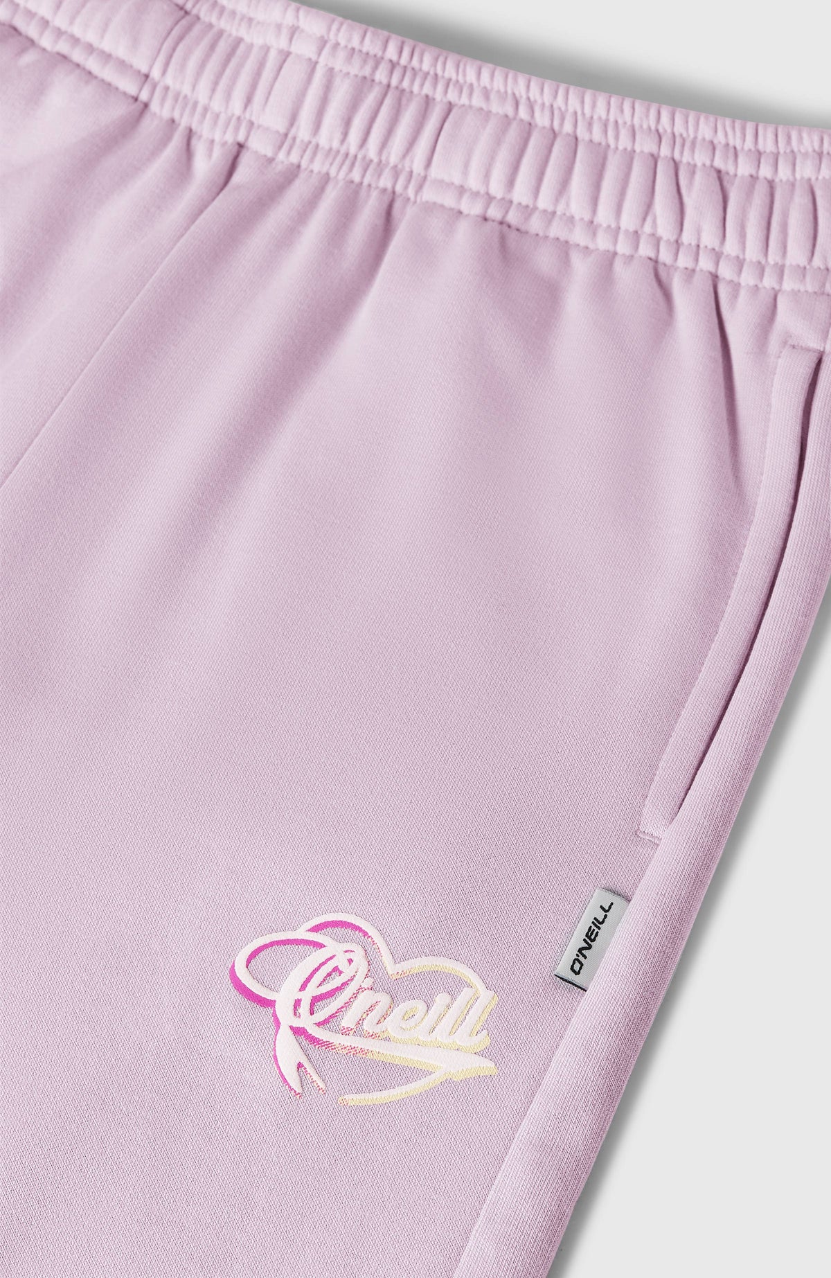 Nahaufnahme der lila Essentials Script Jogginghose für Mädchen mit Logo-Print und seitlicher Tasche