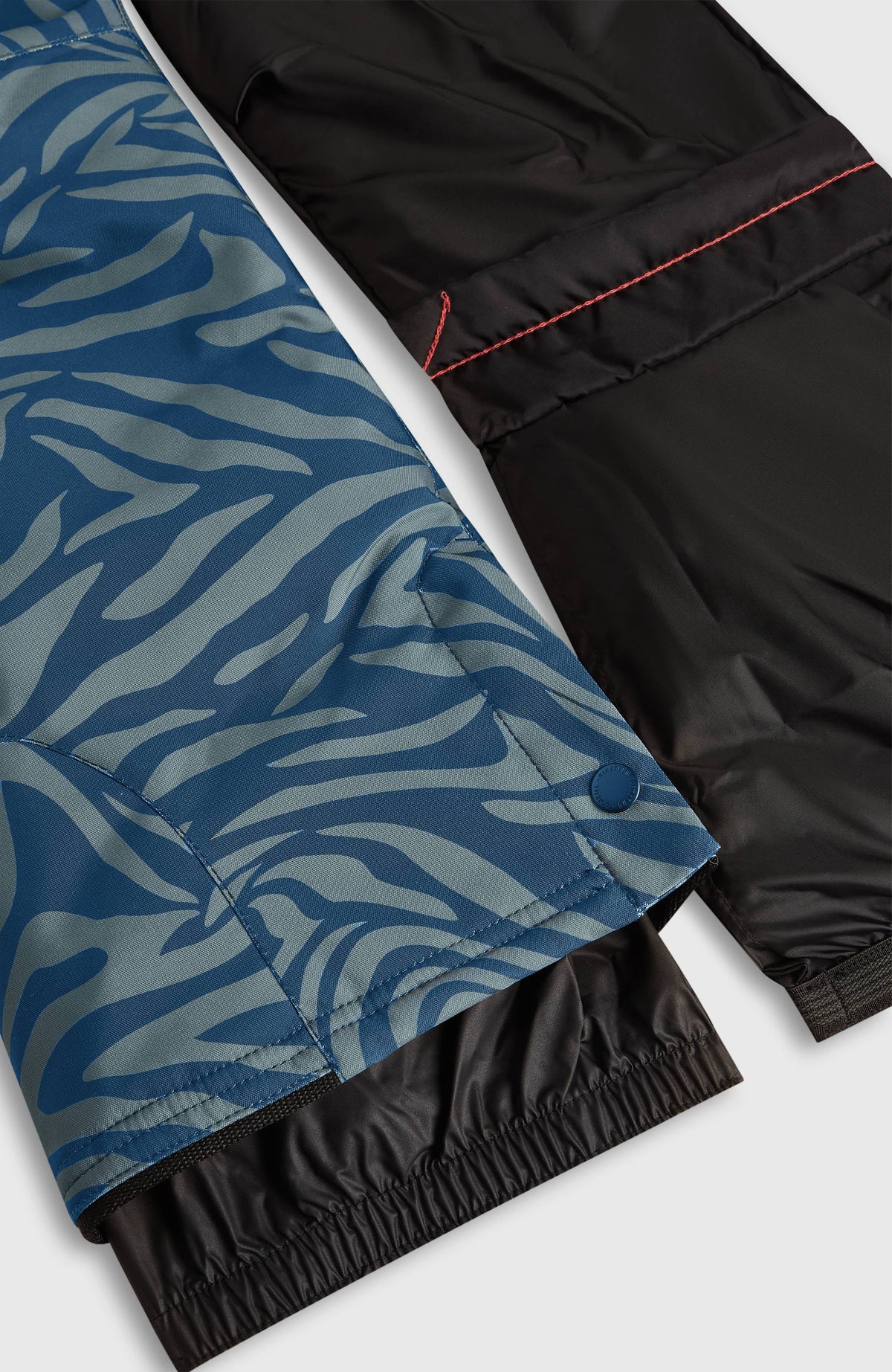 Blaue FWC'Cruz Skihose mit Zebramuster in Grau, Nahaufnahme von Schneefang und Innenfutter