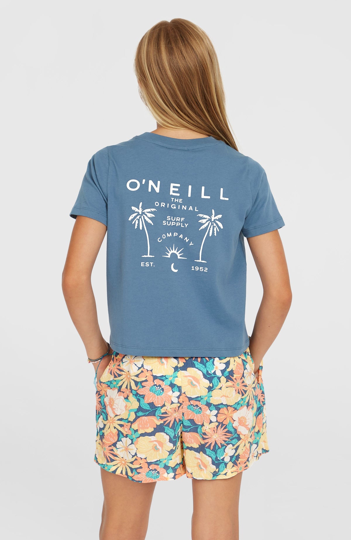 Gewebte Sommershorts für Mädchen, blau mit Blumenmuster in Gelb und Orange, Rückansicht getragen am Model