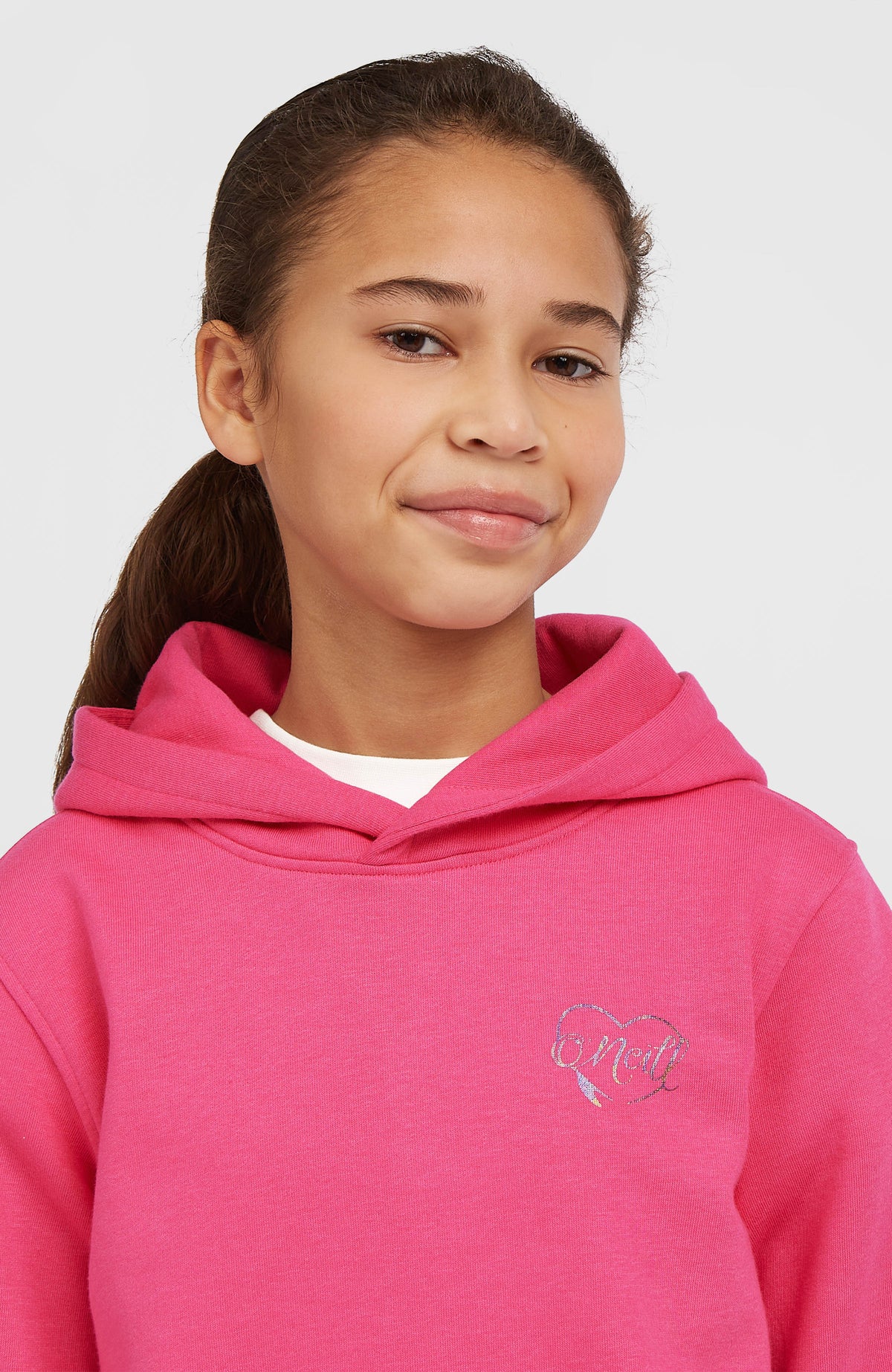 Essentials Hoodie für Mädchen in Pink, Nahaufnahme am Model mit Kapuze und Logo-Print auf der Brust