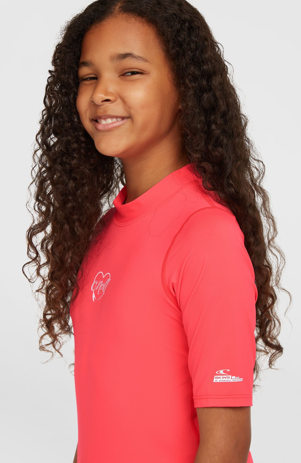 Essentials Shortsleeve-Schwimmshirt für Mädchen, pink mit Logo-Print in Weiß, Nahaufnahme von der Seite am Model