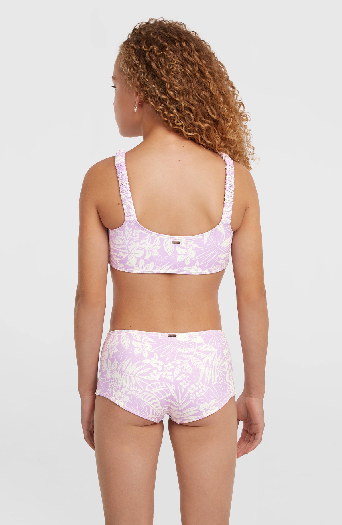 Holiday Bikini-Set für Mädchen, lila mit Blumenmuster in Weiß, Rückansicht am Model, voll bedeckende Bikinihose