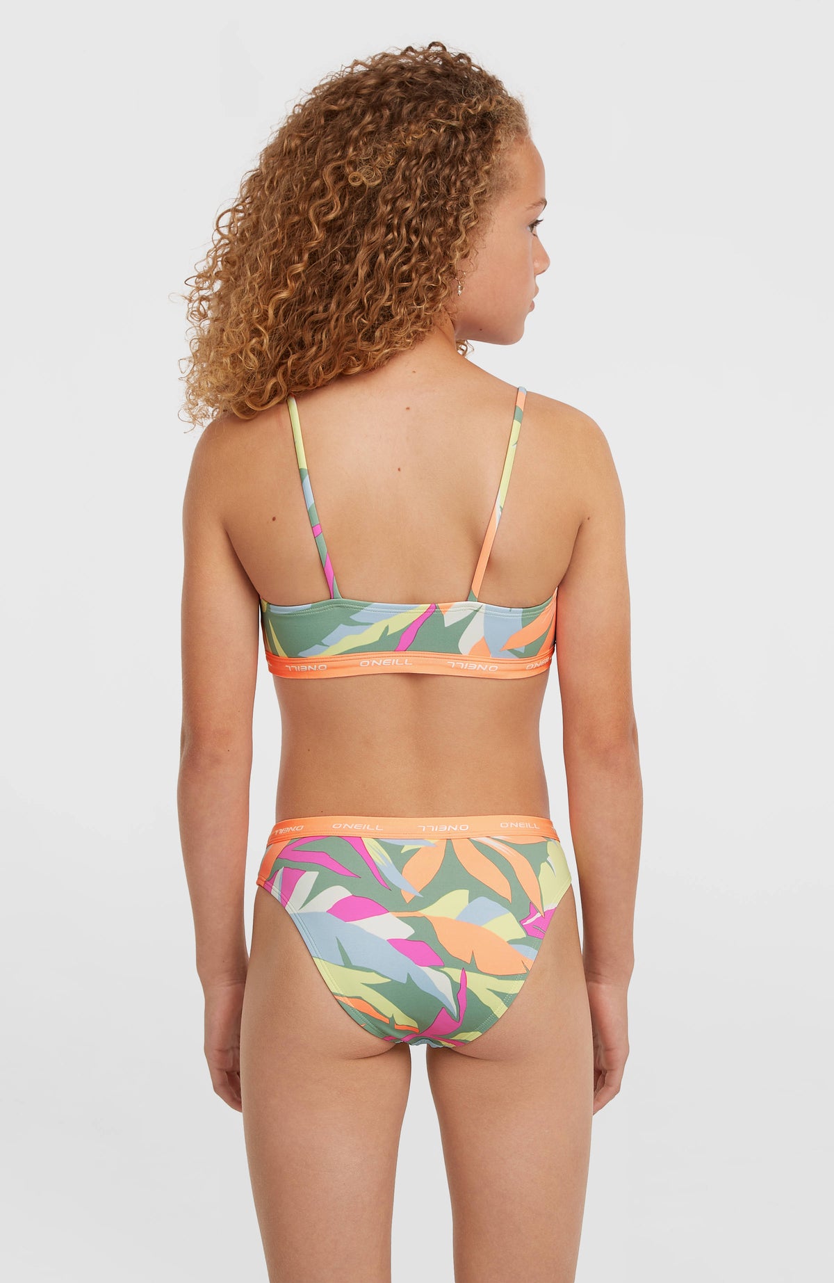 Sport Bikini-Set für Mädchen, grün mit Tropenmuster in Pink und Orange, vollständige Rückansicht am Model
