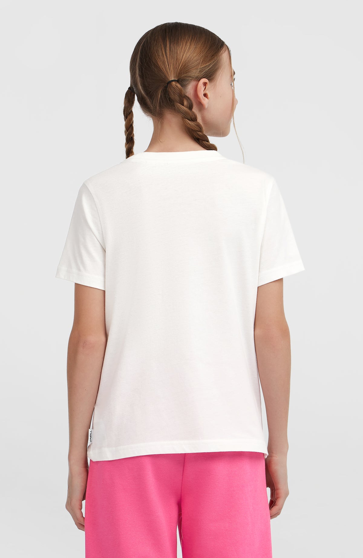 Essentials T-Shirt für Mädchen, weiß mit Logo-Print in Silber, Rückansicht am Model mit kleinem Label am Saum