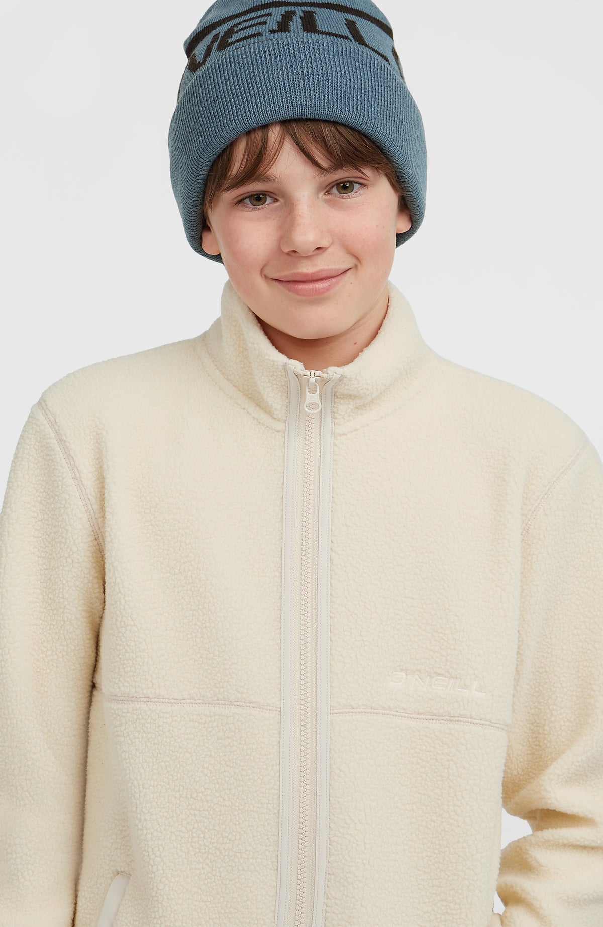 Flauschige Fleecejacke für Jungen, beige, Nahaufnahme am Model, Stehkragen und dezenter Logo-Schriftzug