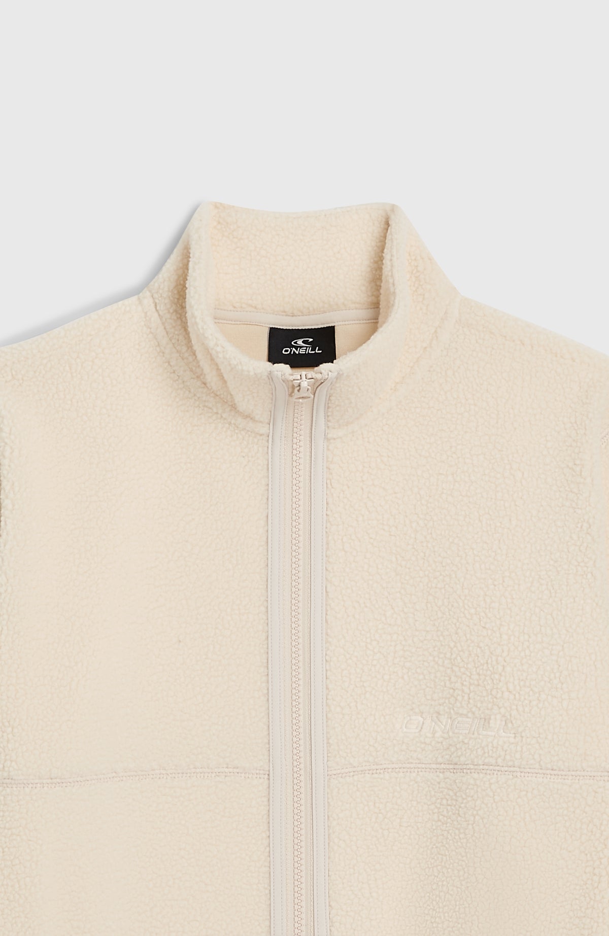 Nahaufnahme der beigen Flauschigen Fleecejacke, flach liegend von vorne, Stehkragen mit Logo-Etikett