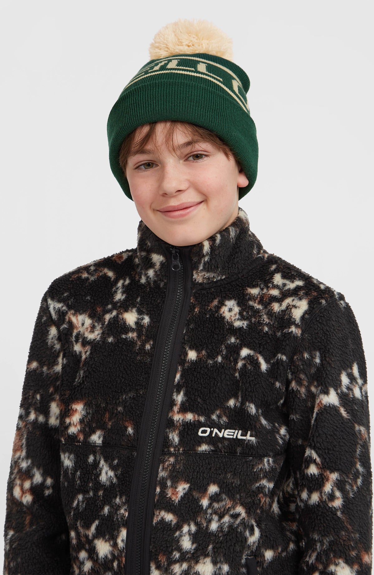 Flauschige Fleecejacke für Jungen, schwarz mit Allover-Muster in Beige, Vorderansicht am Model mit Logo-Stickerei