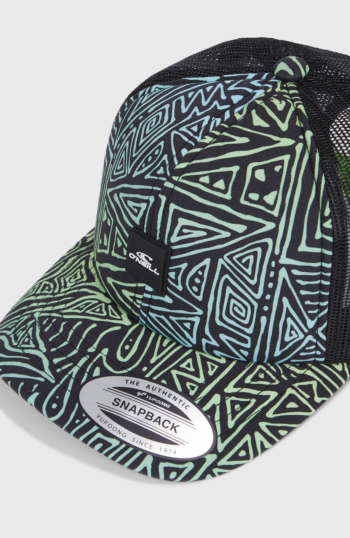 Nahaufnahme von Schirm und Logo-Patch der blauen Flood Trucker Cap mit Grafikmuster in Grün