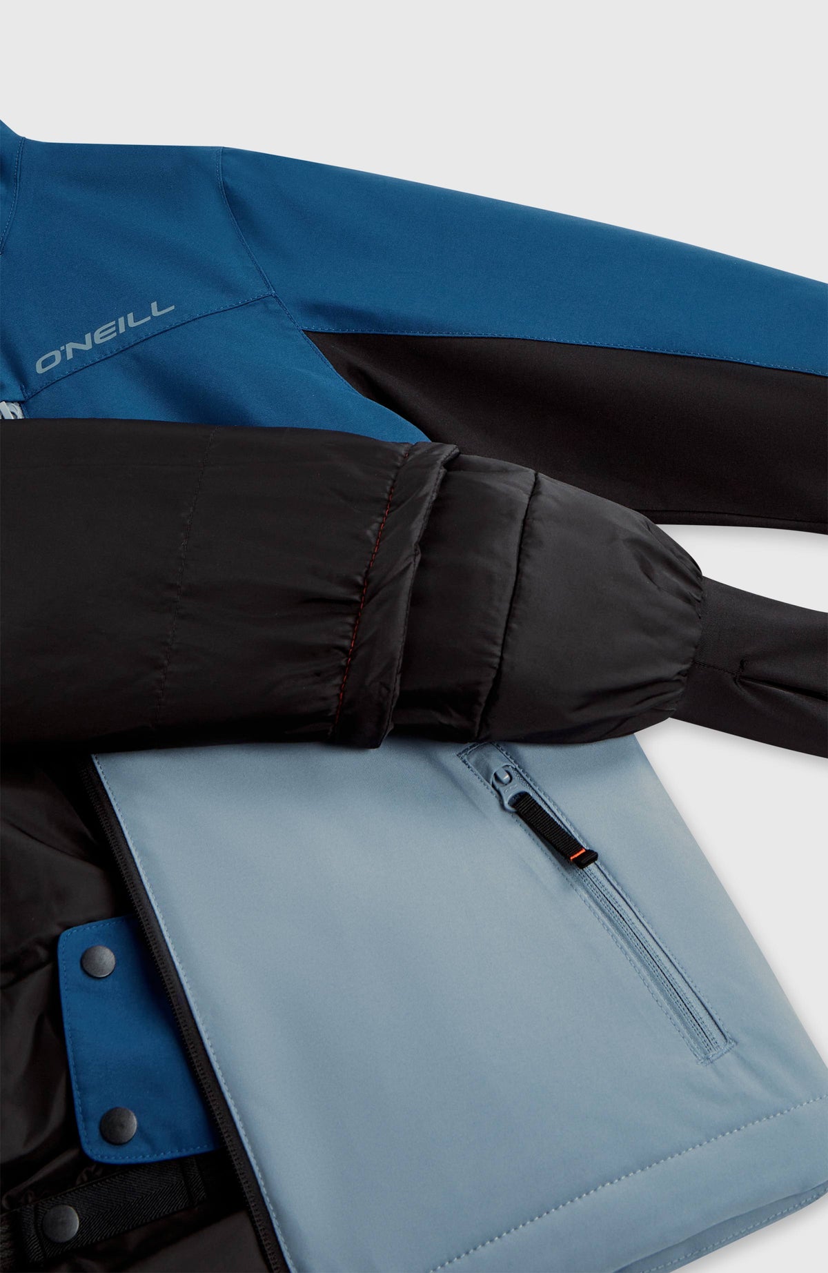Nahaufnahme der blauen FWC'Cruz Triple Skijacke mit Innenfutter, Reißverschlusstasche und Druckknöpfen