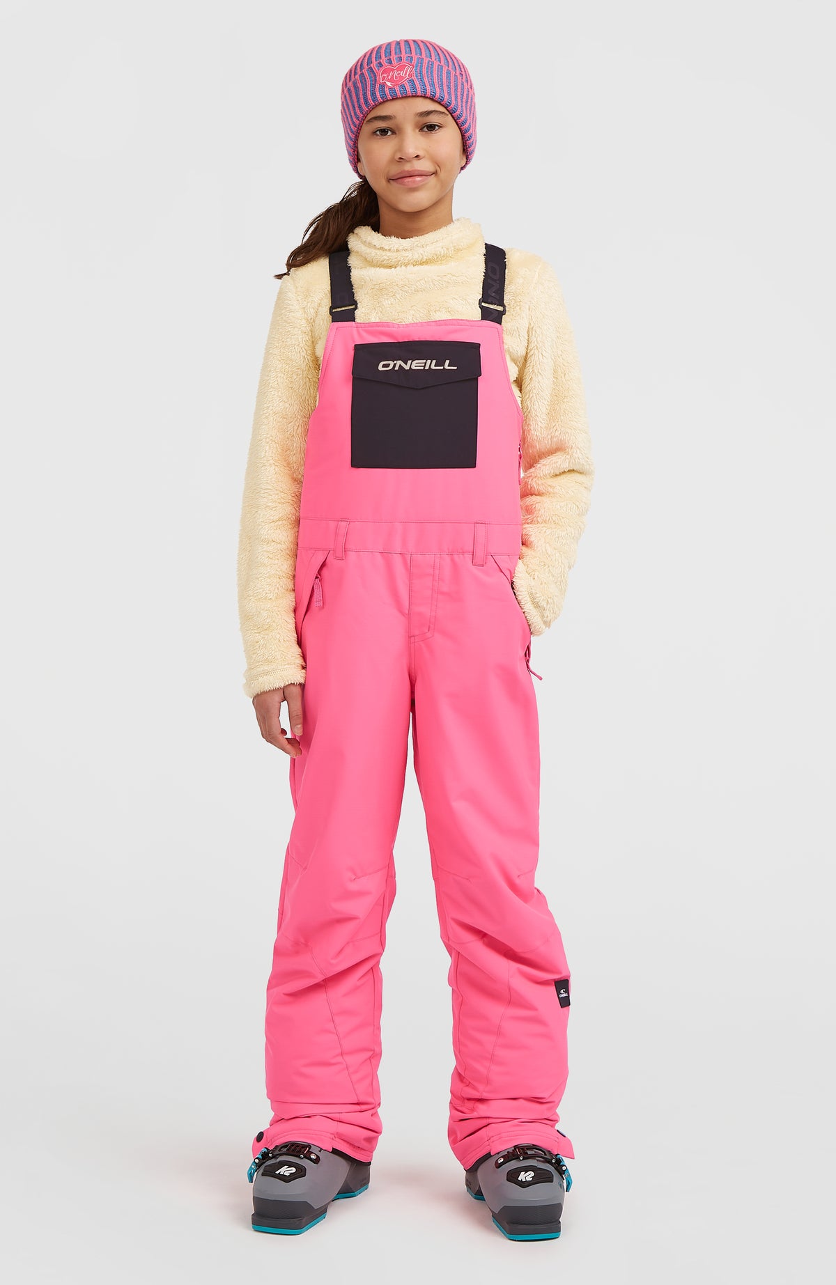 O'Neill FWC'Cruz Bib Skihose für Kinder, pink, getragen am Model in der Vorderansicht mit Brusttasche
