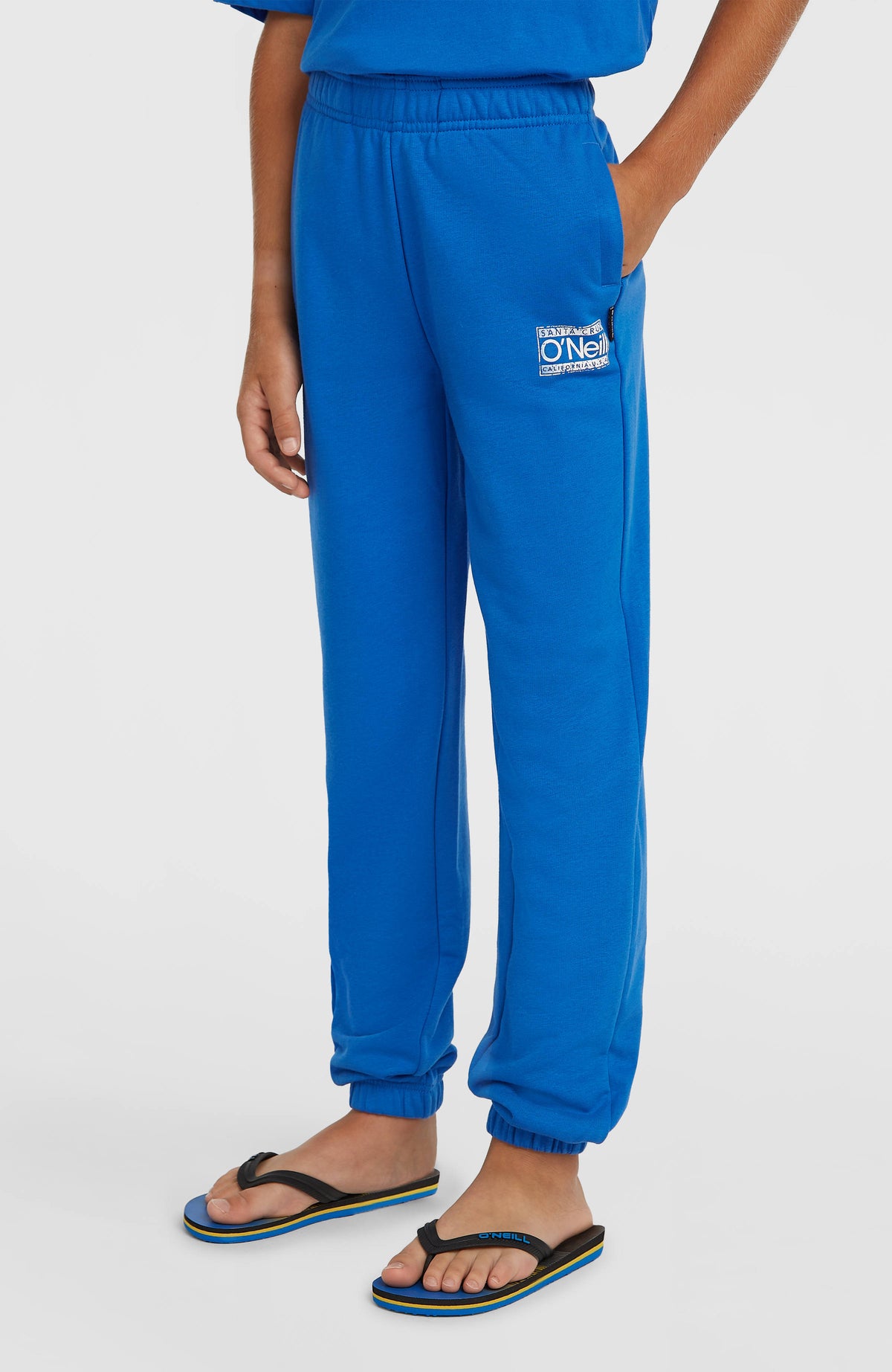Blaue Cali Jogginghose für Jungen mit Logo-Print in Weiß, getragen am Model, schräge Seitenansicht