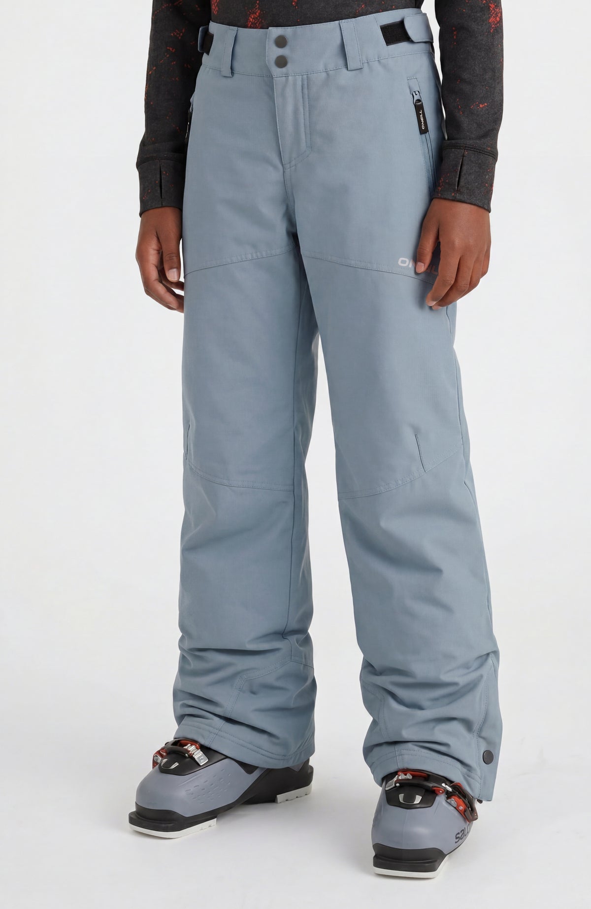 O'Neill FWC'Cruz Skihose für Jungen, blau, Vorderansicht am Model mit Skischuhen und Reißverschlusstasche