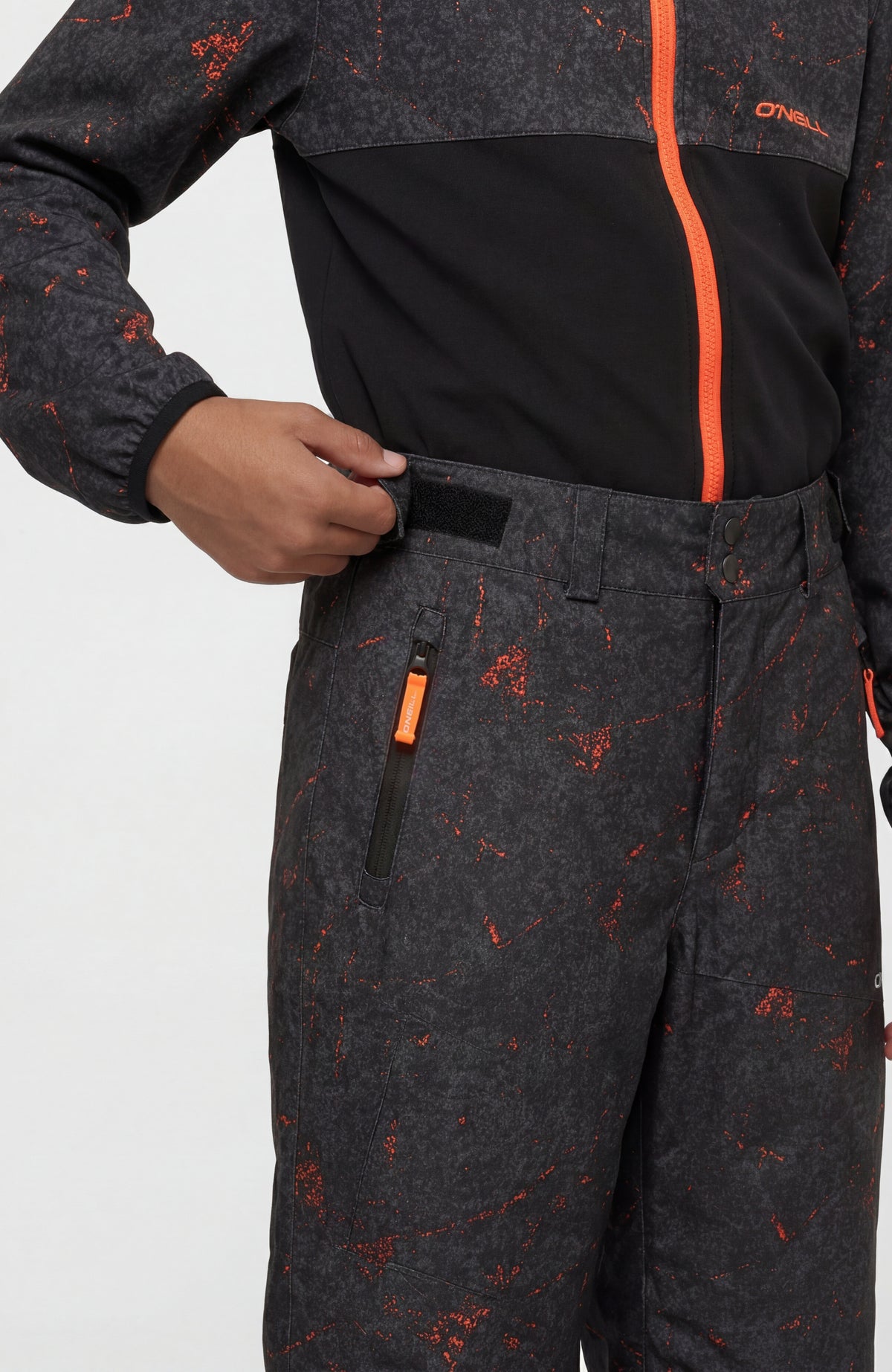 Schwarze FWC'Cruz Skihose mit Sprenkelmuster in Orange, Nahaufnahme von Bund und Reißverschlusstasche