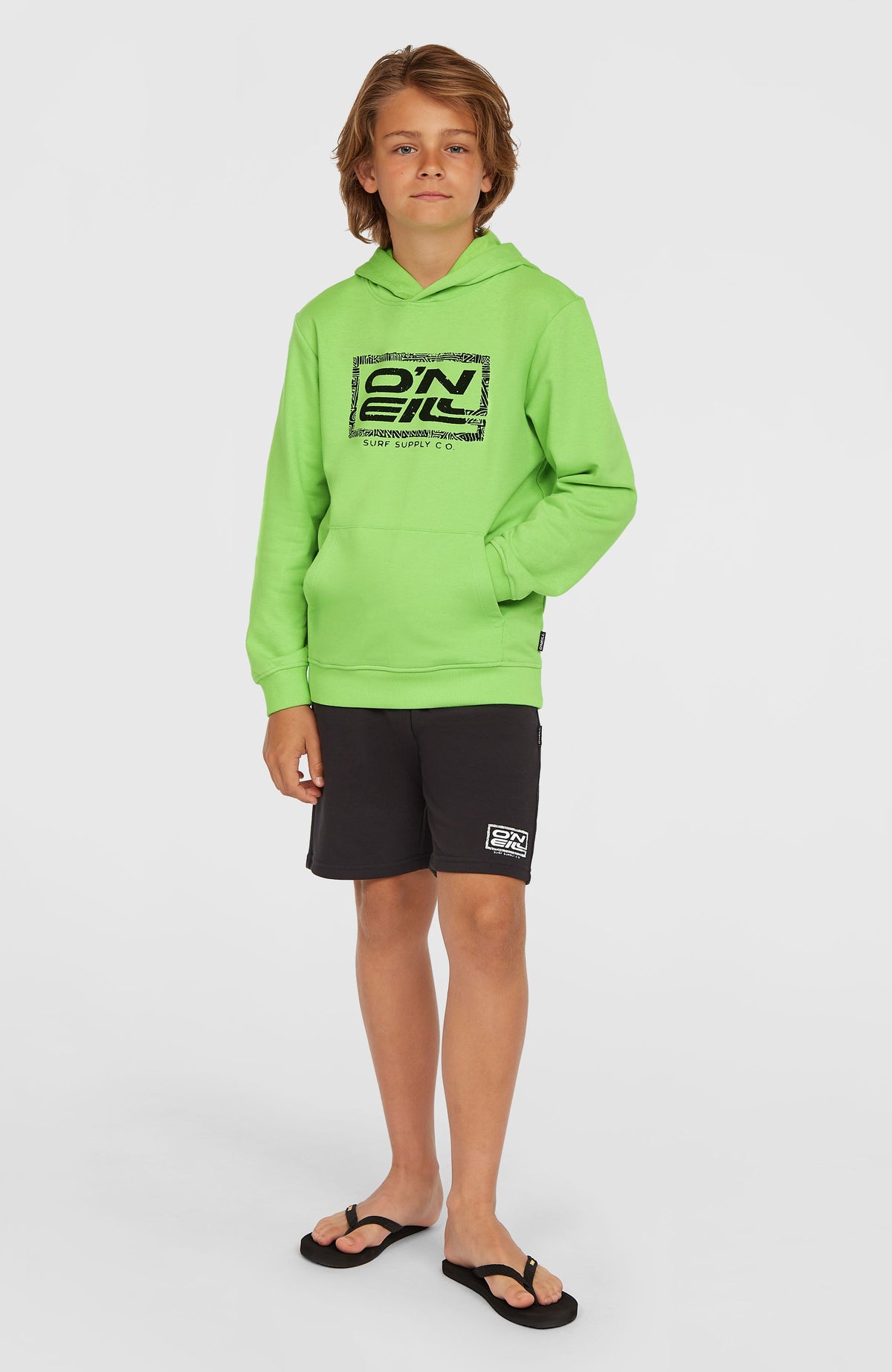 Logo Hoodie für Jungen, grün mit Logo-Print in Schwarz, Ganzkörperansicht am Model mit Kängurutasche
