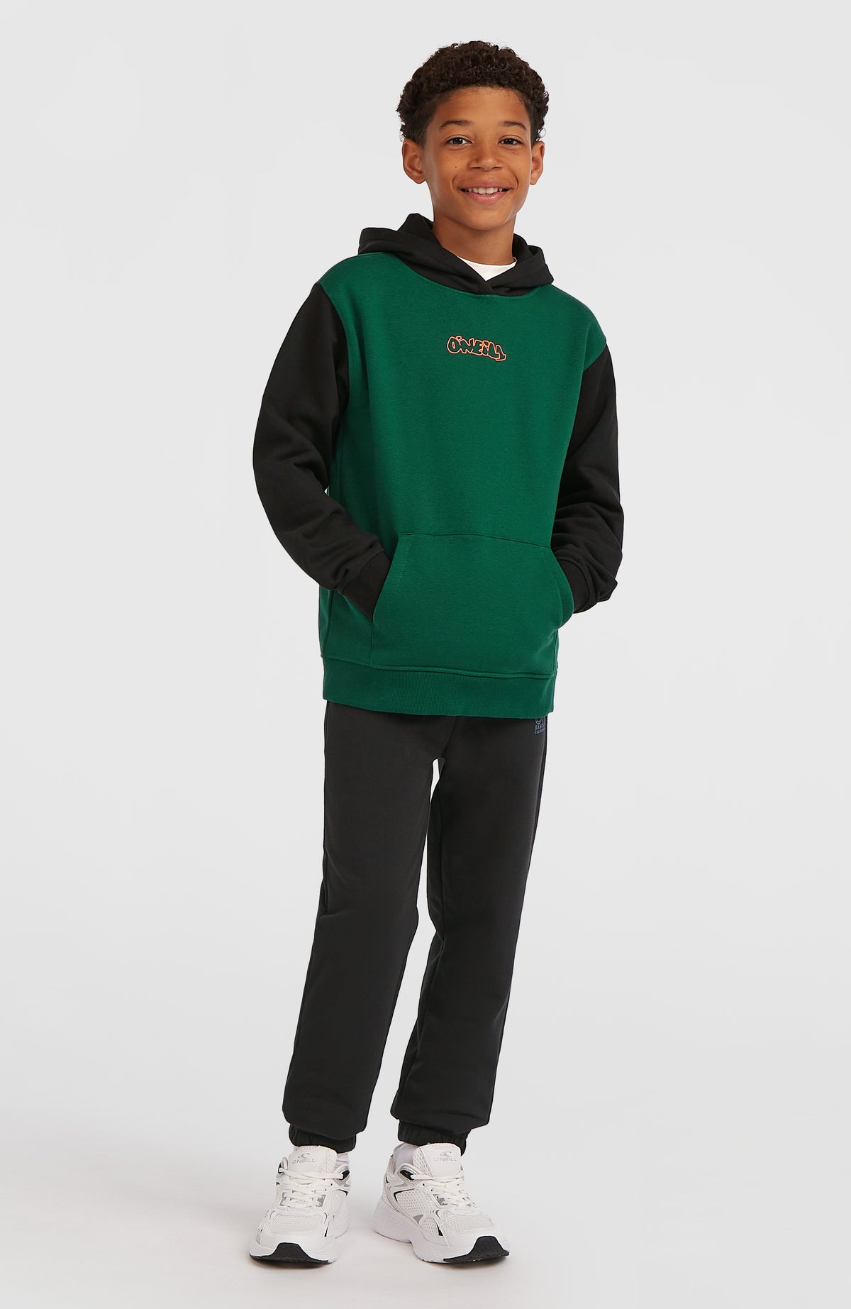 FWC'Play Hoodie für Jungen, grün mit Logo-Print in Orange, stehende Ganzkörperansicht getragen am Model