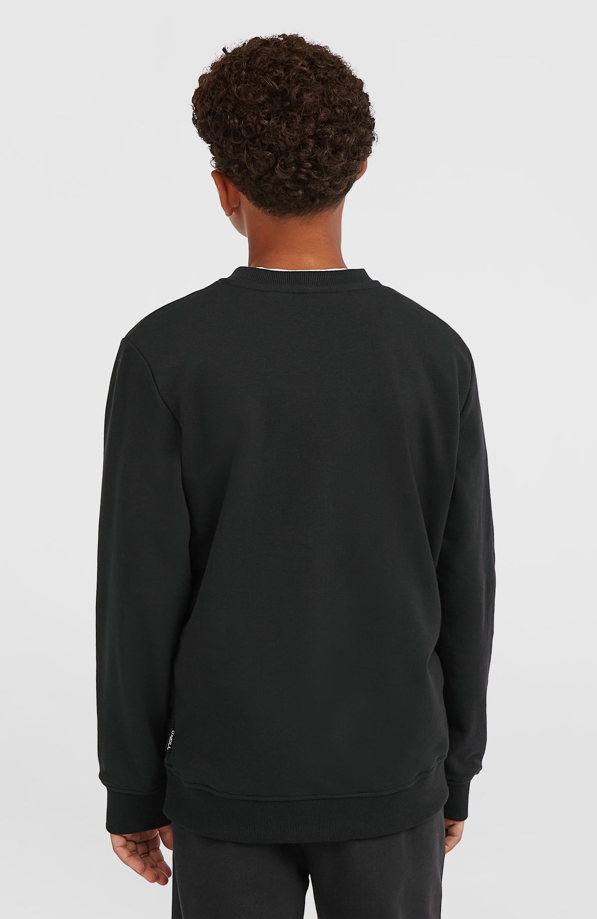 Essentials Crew Sweatshirt für Jungen, schwarz, Rückansicht am Model mit kleinem seitlichen Logo-Label am Saum