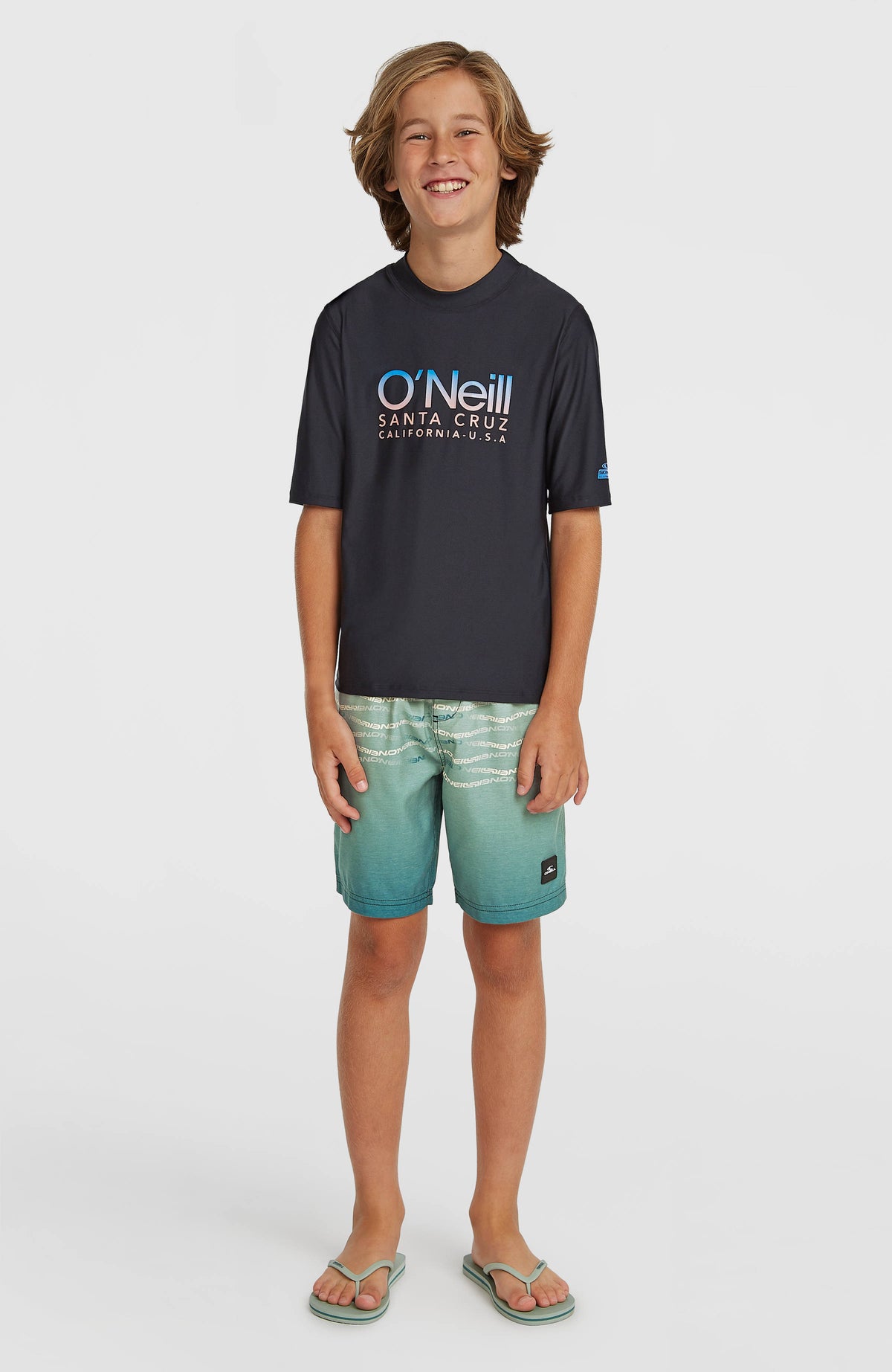 First Badehose für Jungen, grün mit Logo-Print in Weiß, vollständige Frontansicht getragen am Model