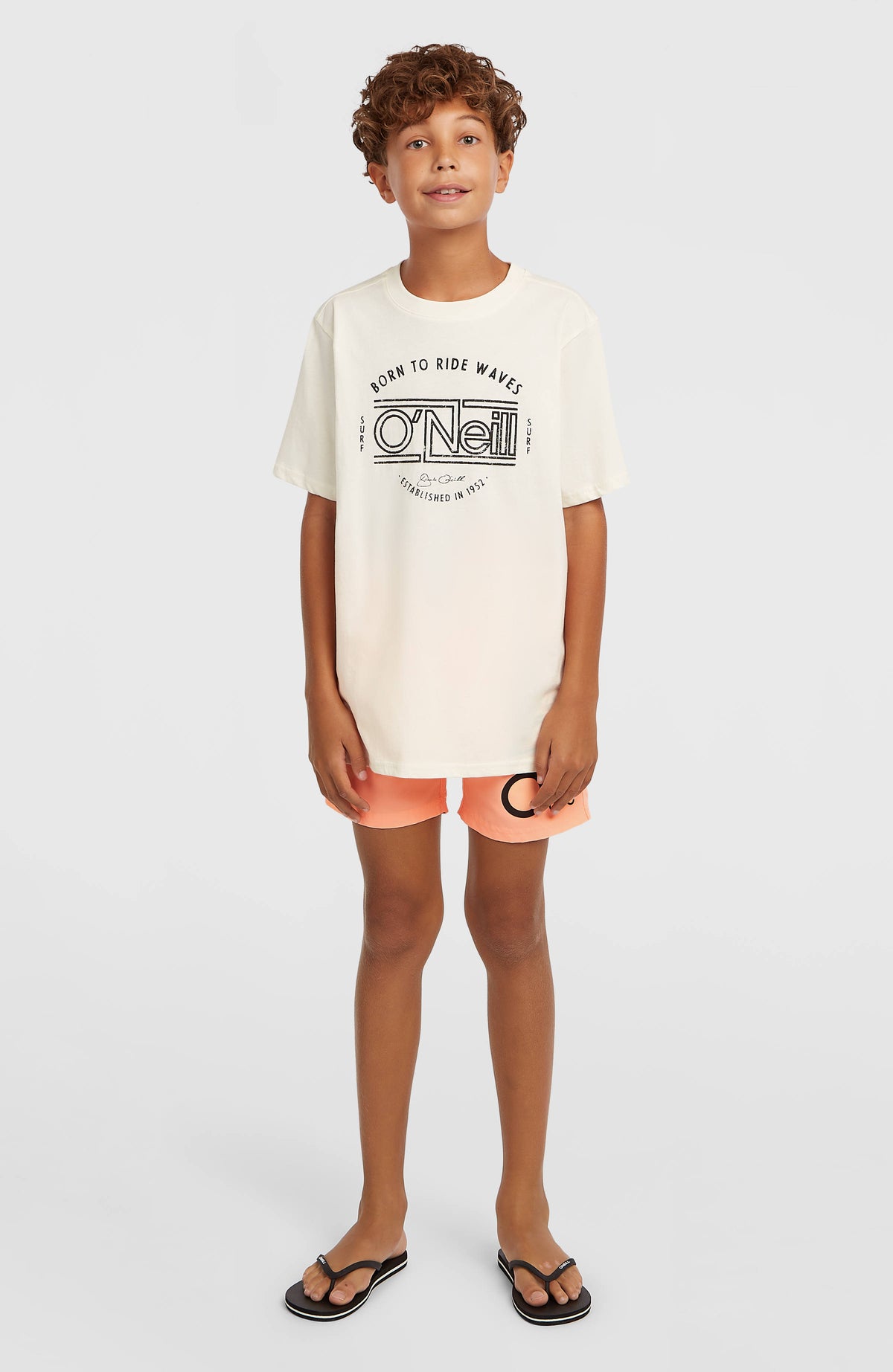 Cali Badehose für Jungen, orange mit Logo-Print in Schwarz, Ganzkörperansicht von vorne am Model