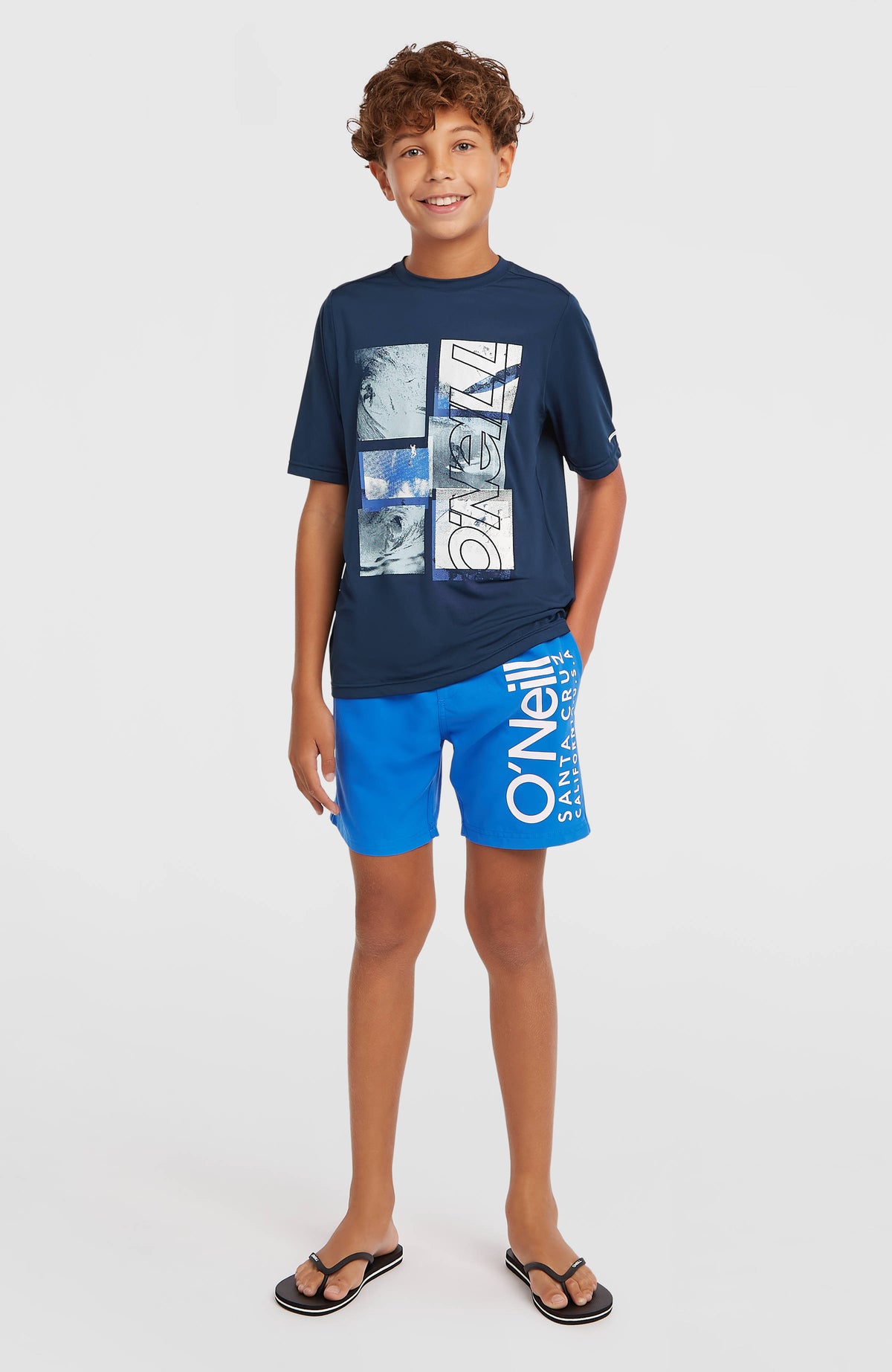 Cali Badehose für Jungen, blau mit Logo-Print in Weiß, Ganzkörperansicht am Model von vorne