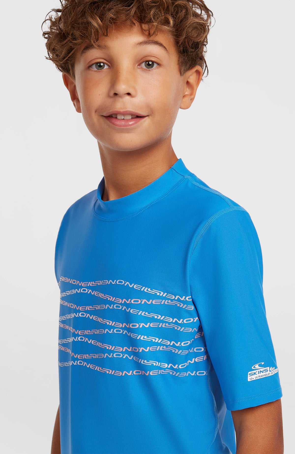 Graphic Shortsleeve-UV-Shirt für Jungen, blau mit Logo-Print in Rosa, Halbprofil am Model, Logo am Ärmel