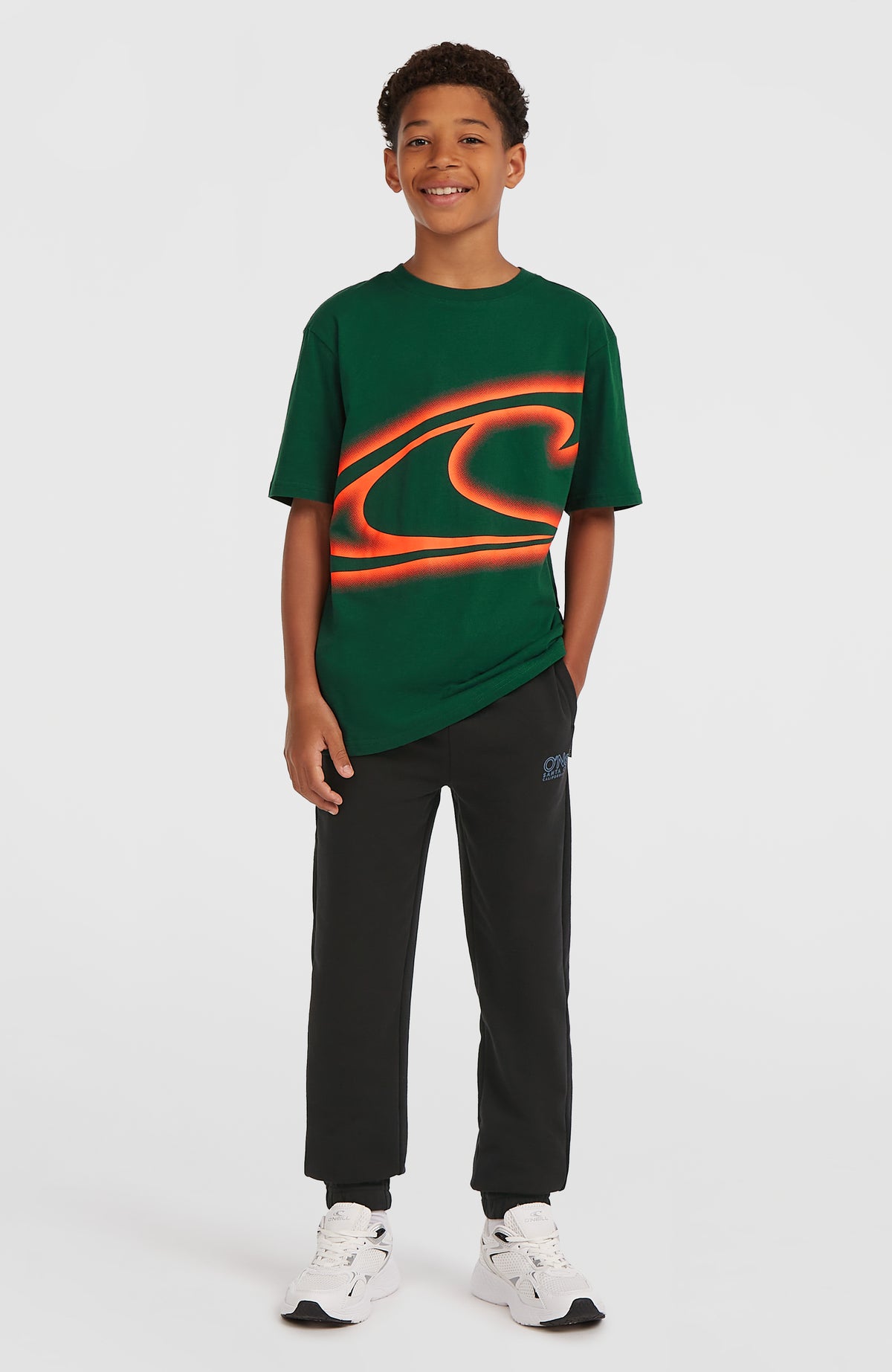 Wave T-Shirt für Jungen, grün mit Logo-Print in Orange, getragen am Model, Ganzkörperansicht
