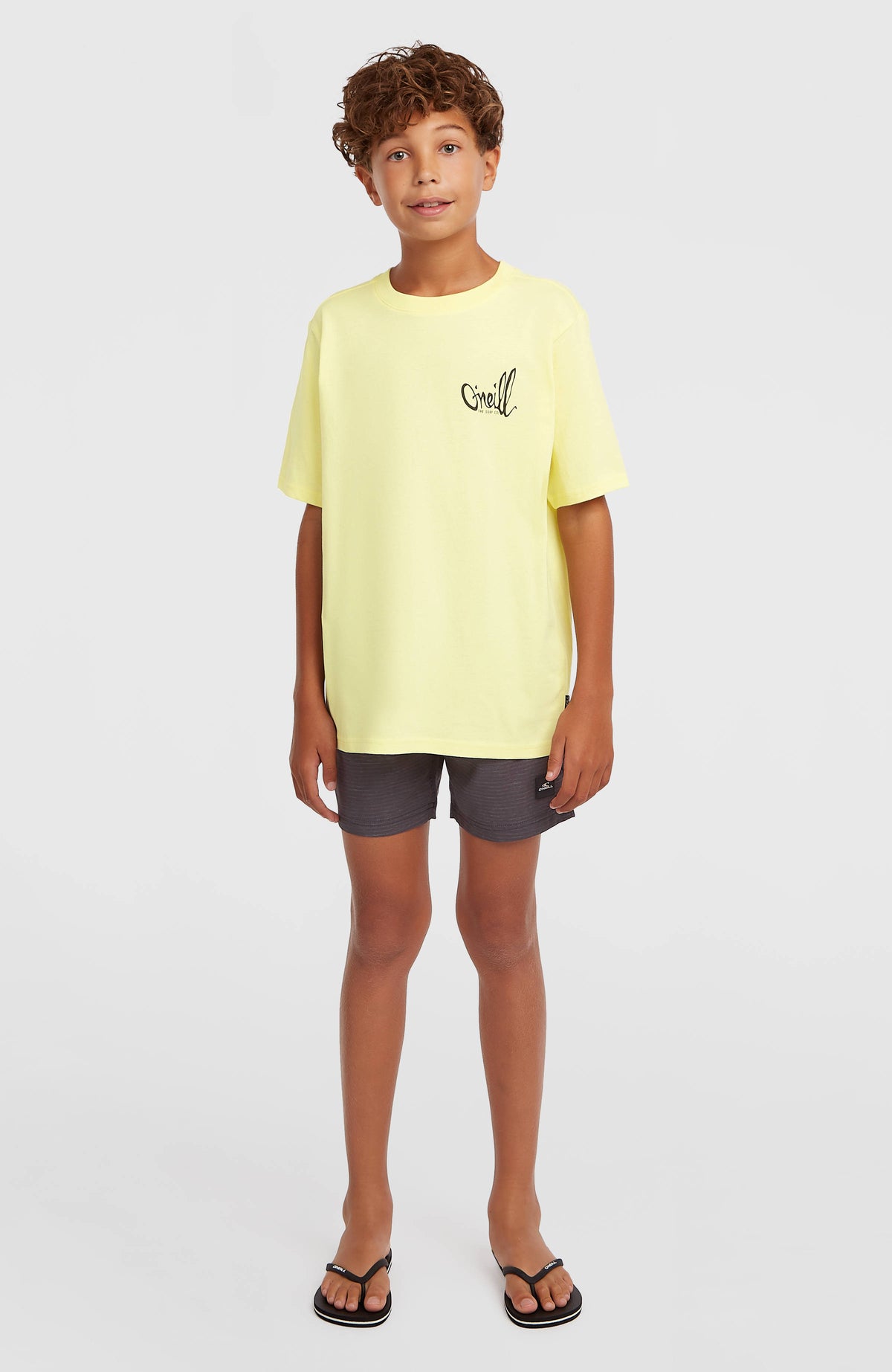 Chest-Print T-Shirt für Jungen, gelb mit Logo-Print in Schwarz, Ganzkörperansicht von vorne am Model