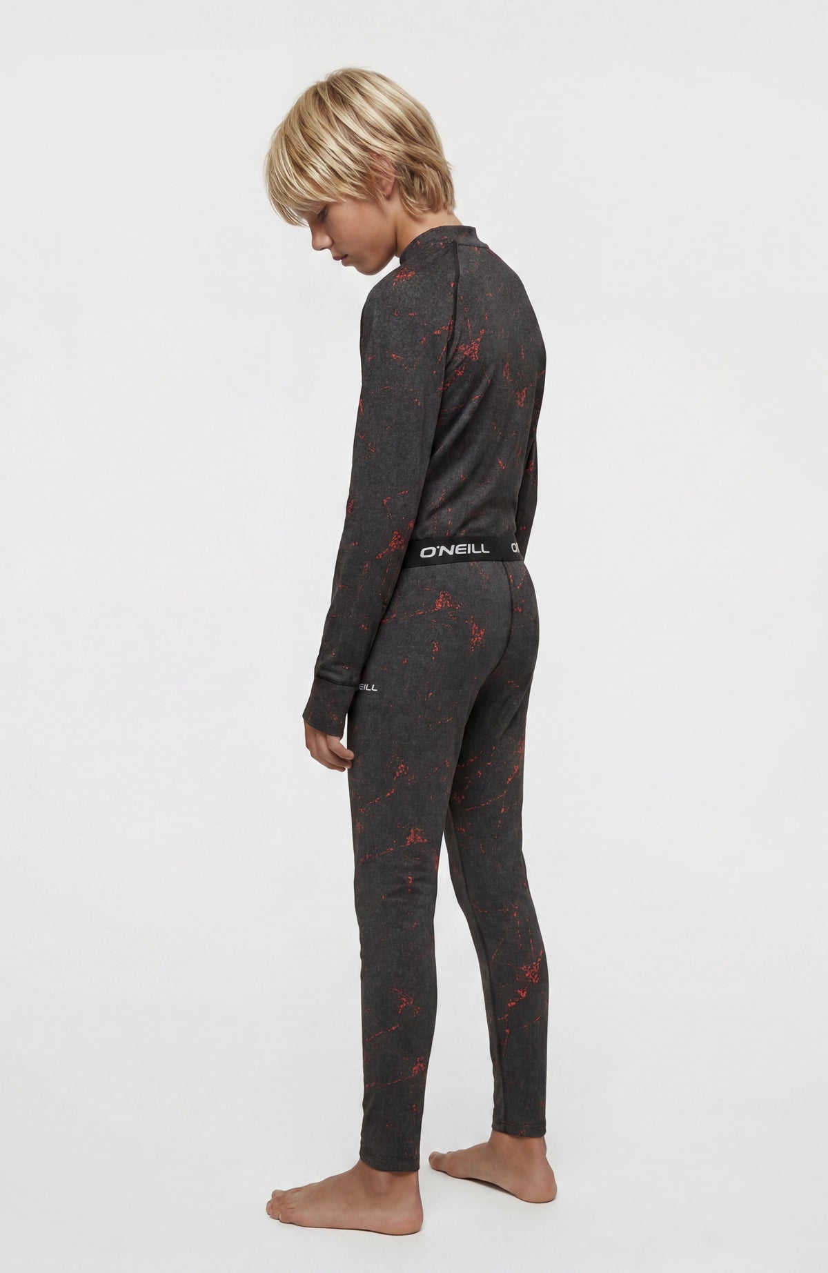 Baselayer-Set für Jungen, schwarz mit Sprenkelmuster in Rot, Seitenansicht am Model mit Logo-Bund