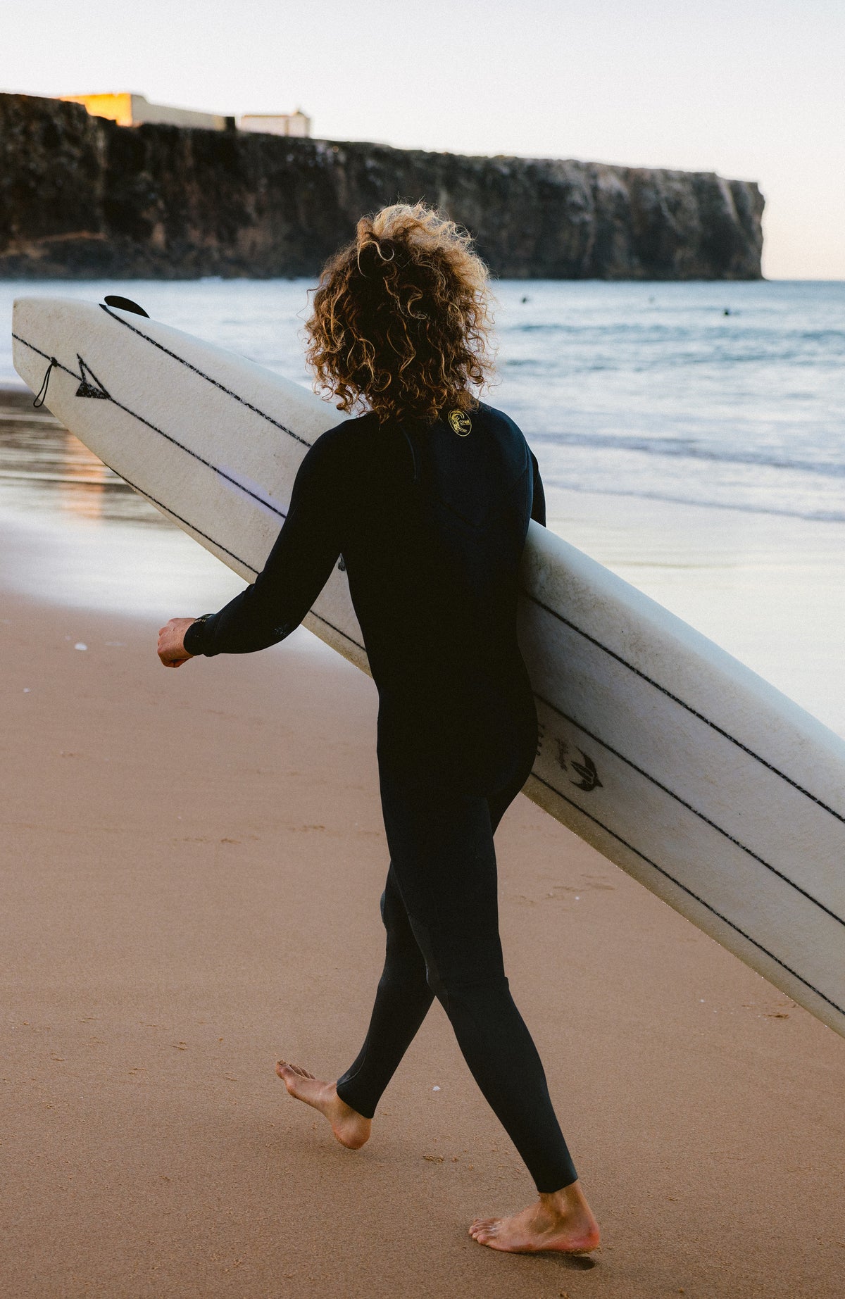 Schwarzer O'Riginals RG8 Neoprenanzug für Herren, getragen am Model am Strand, Ganzkörperansicht von hinten